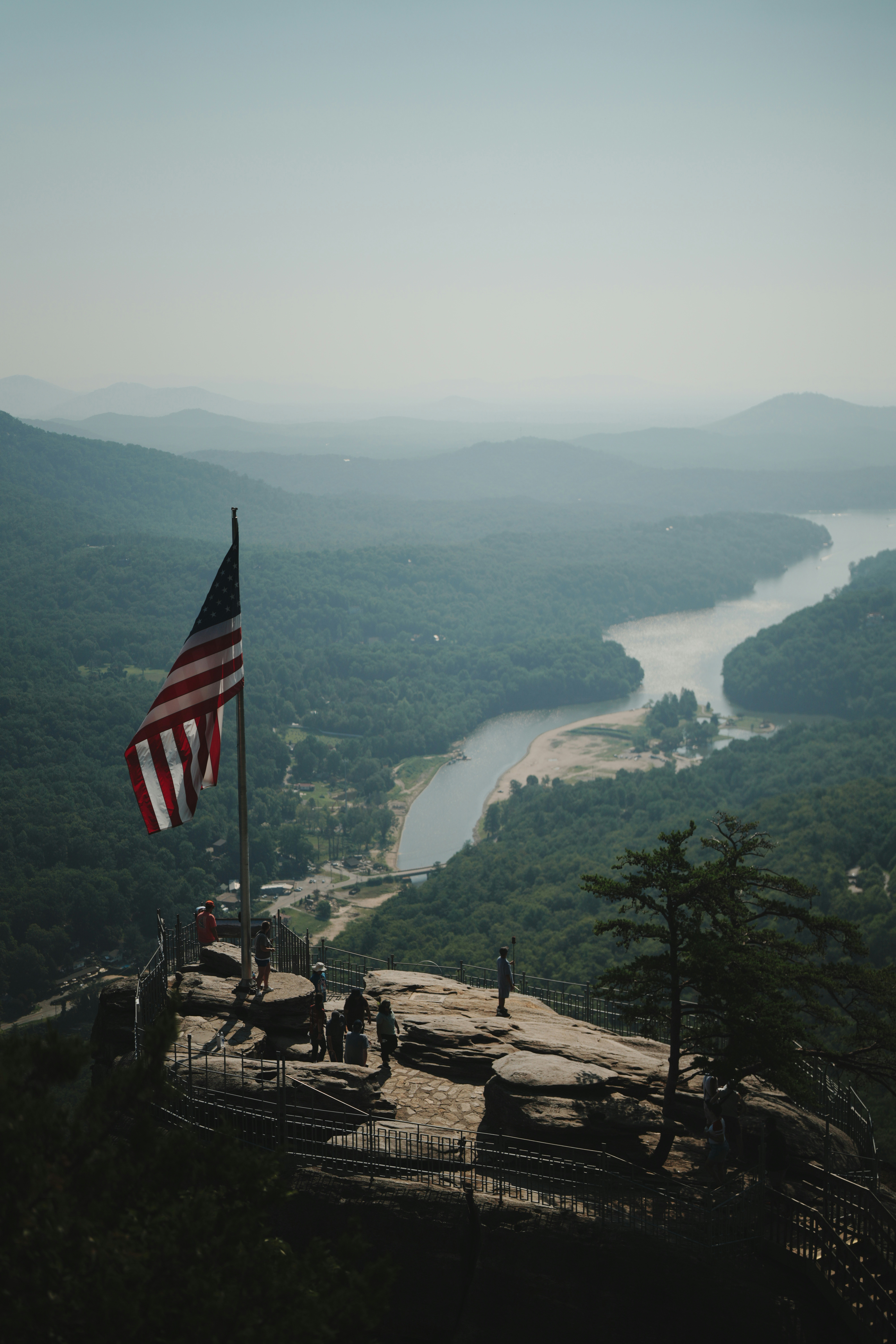 Amerikanische Flagge auf einem Berggipfel mit Blick auf ein Flusstal.