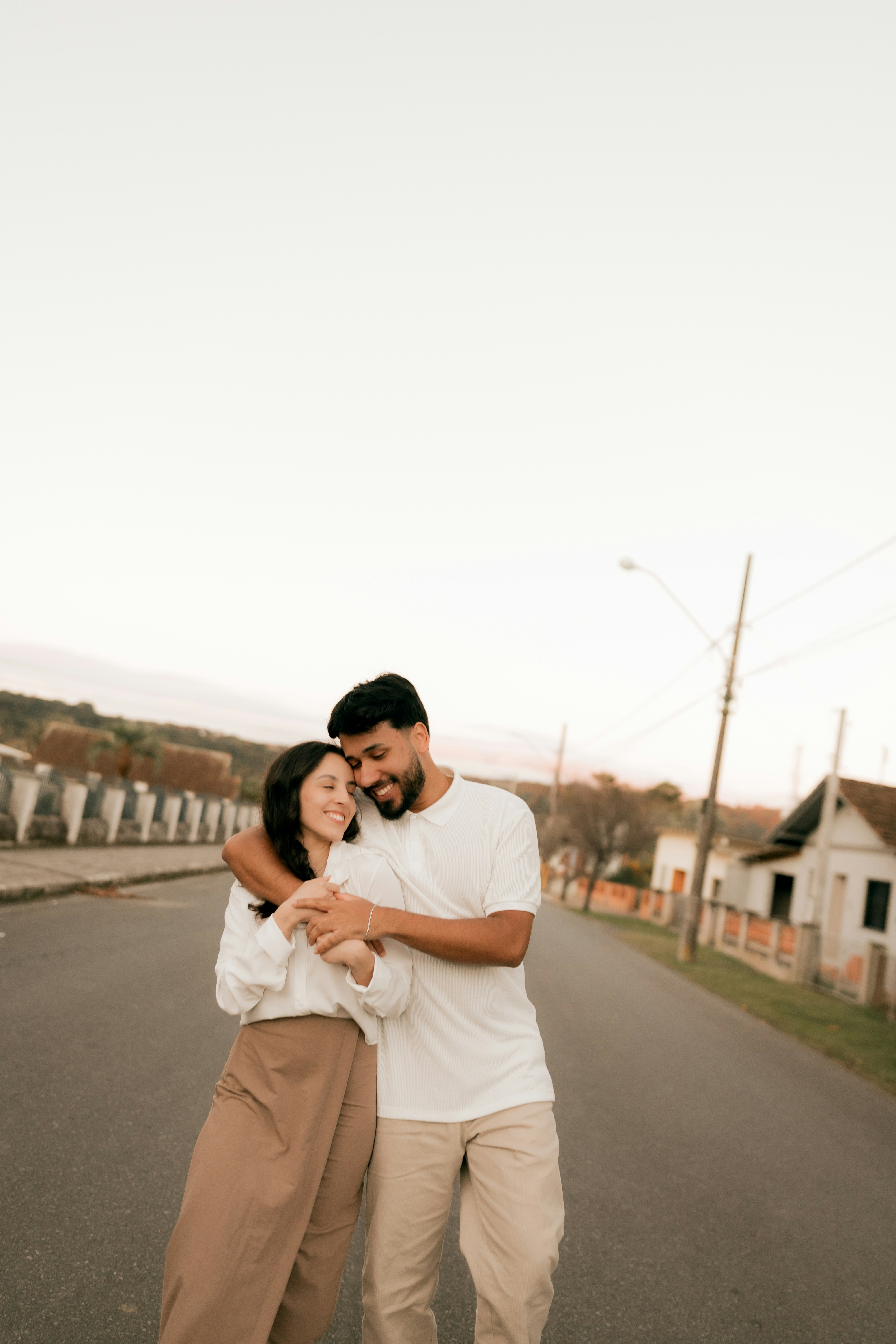 A smiling couple embraces on a quiet street