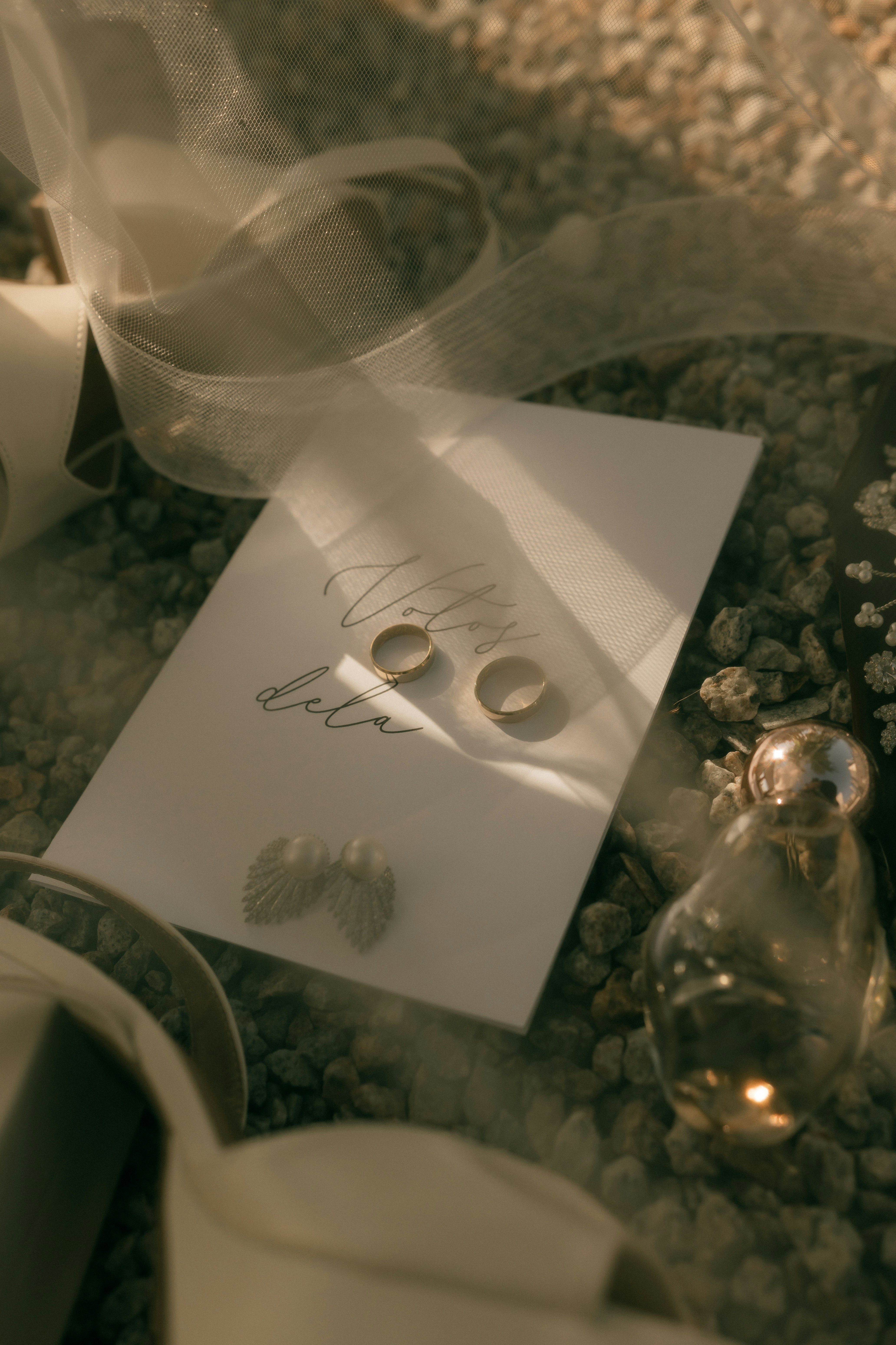 Elegantes anillos de boda, pendientes y perfume sobre una superficie texturizada.