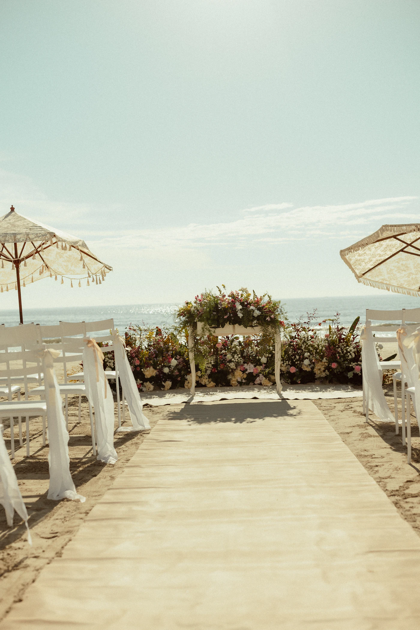 Bridal jumpsuits for non-traditional beach weddings — A close-up of elegant flat sandals paired with a flowing bridal jumpsuit hem