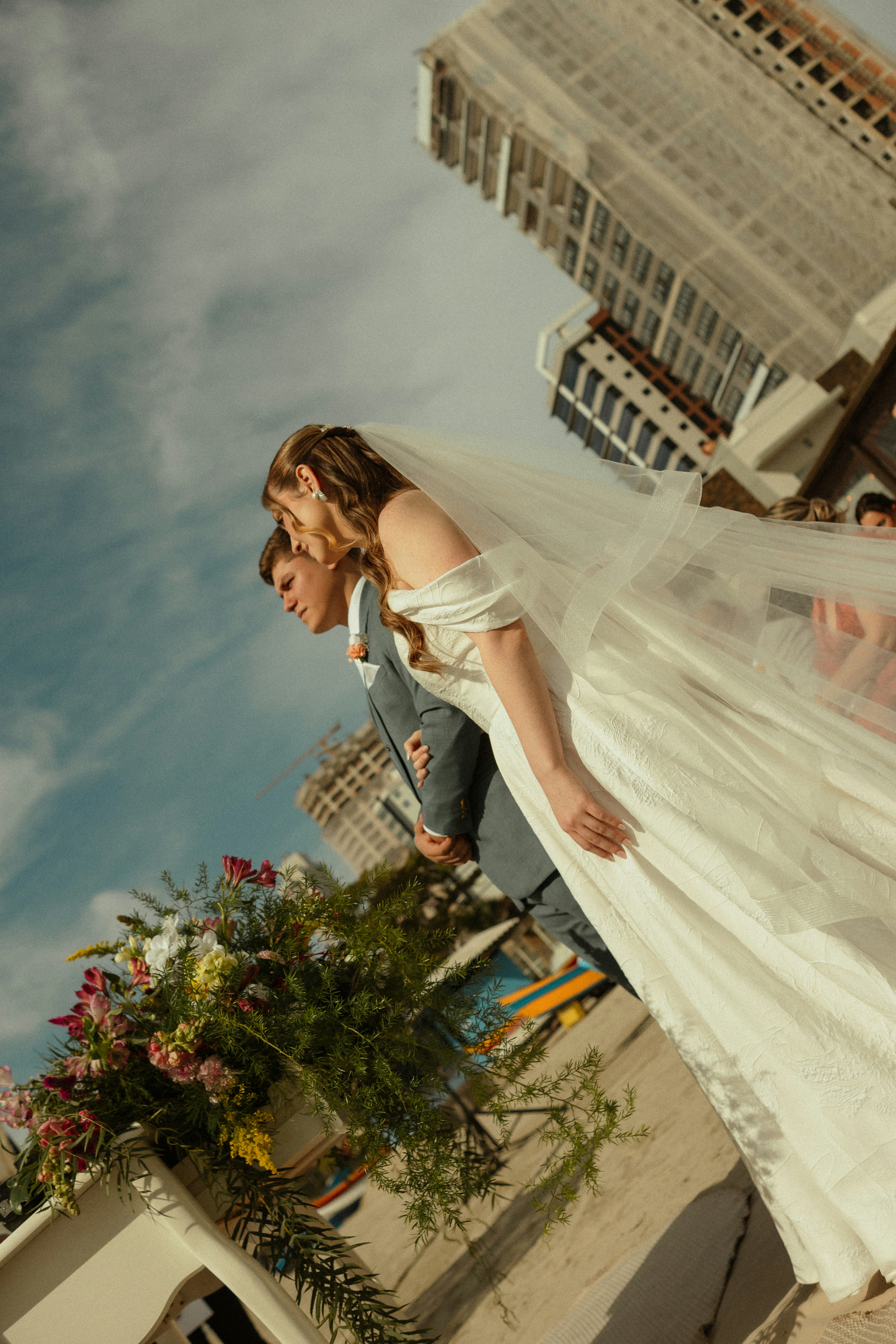 Pareja de boda al aire libre con edificios de la ciudad y flores.