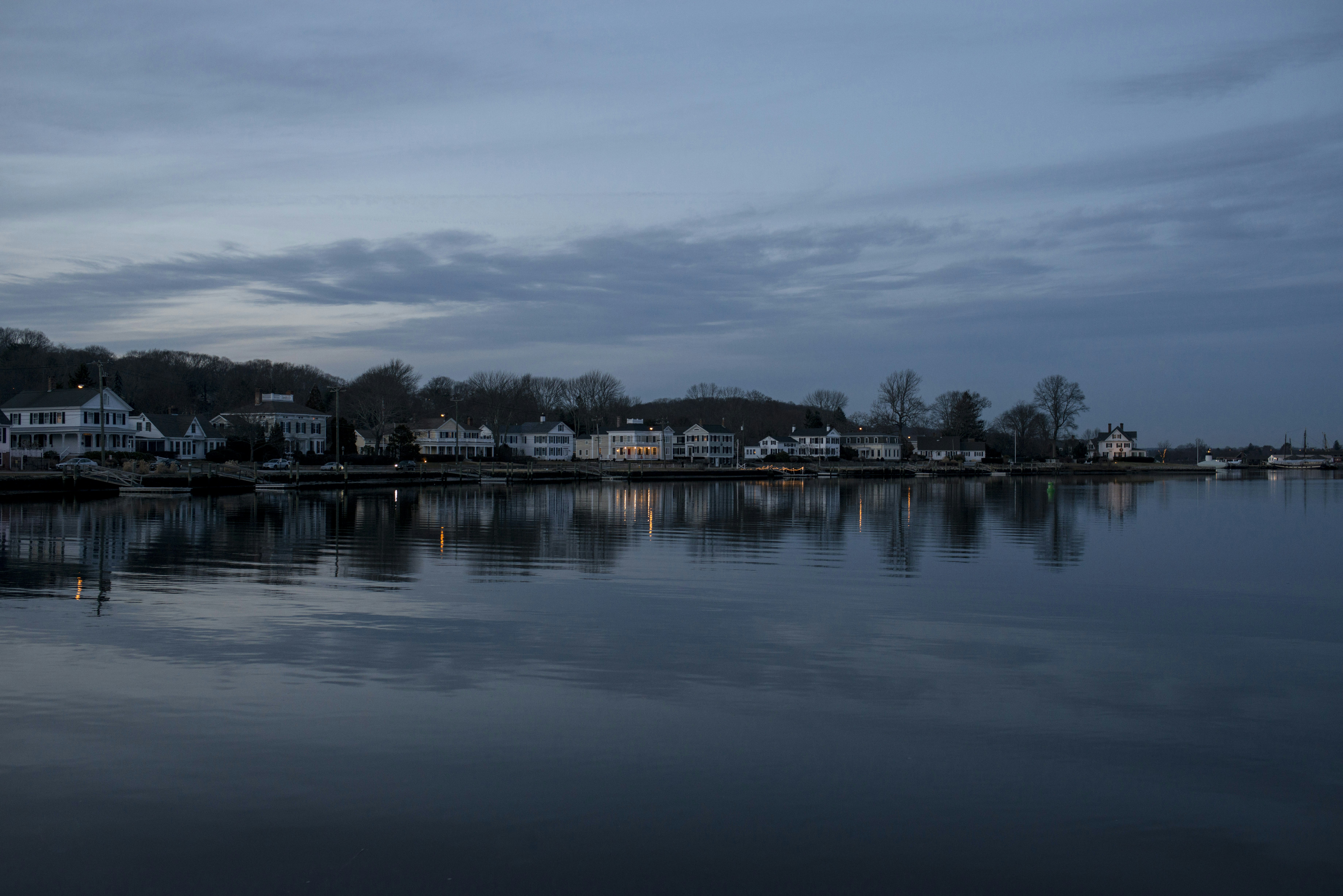 Coastal town with lights reflecting on still water at dusk.