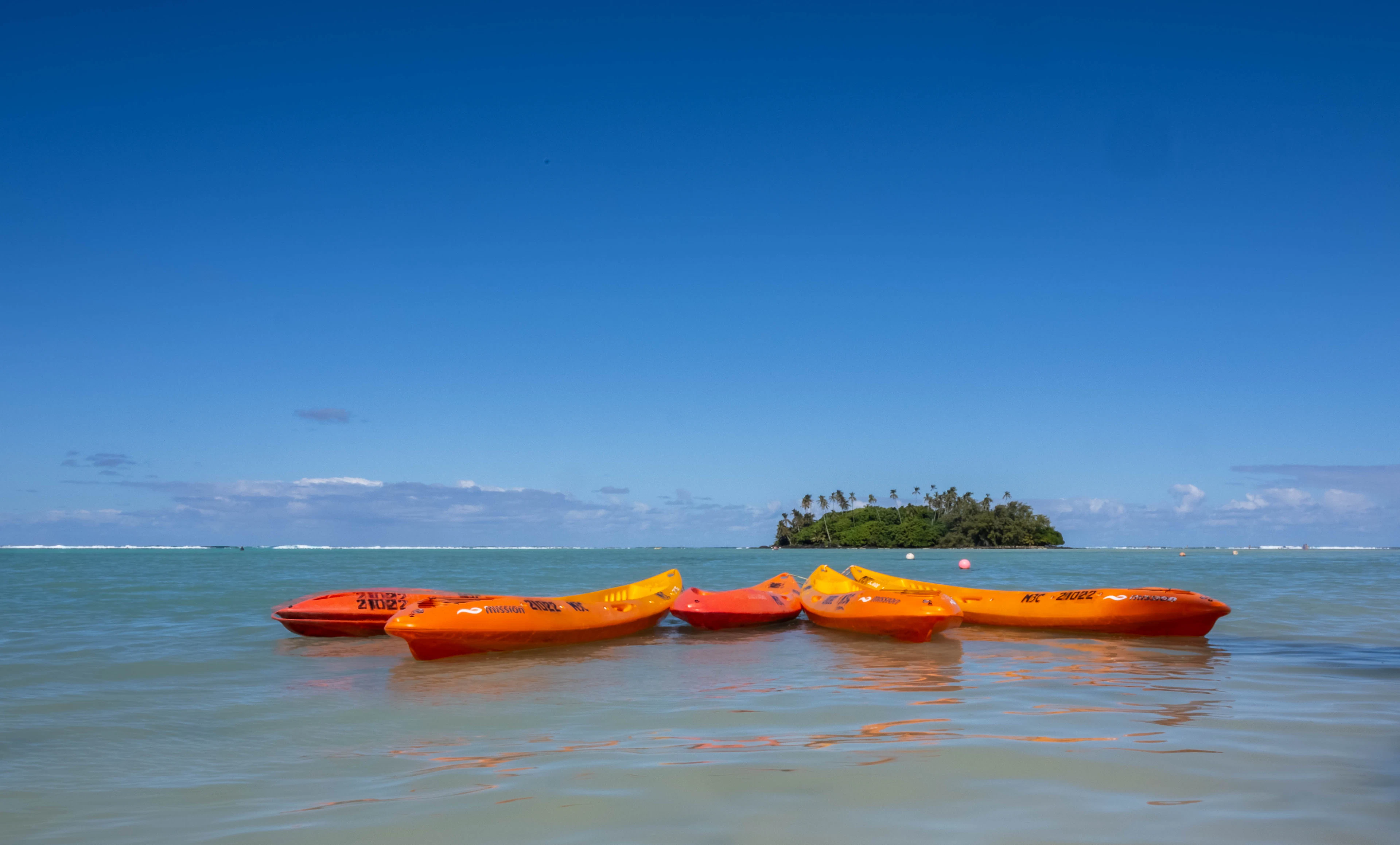 Orange kayaks on the calm Muri lagoon, with the motu of Taakoka beyond, Rarotonga