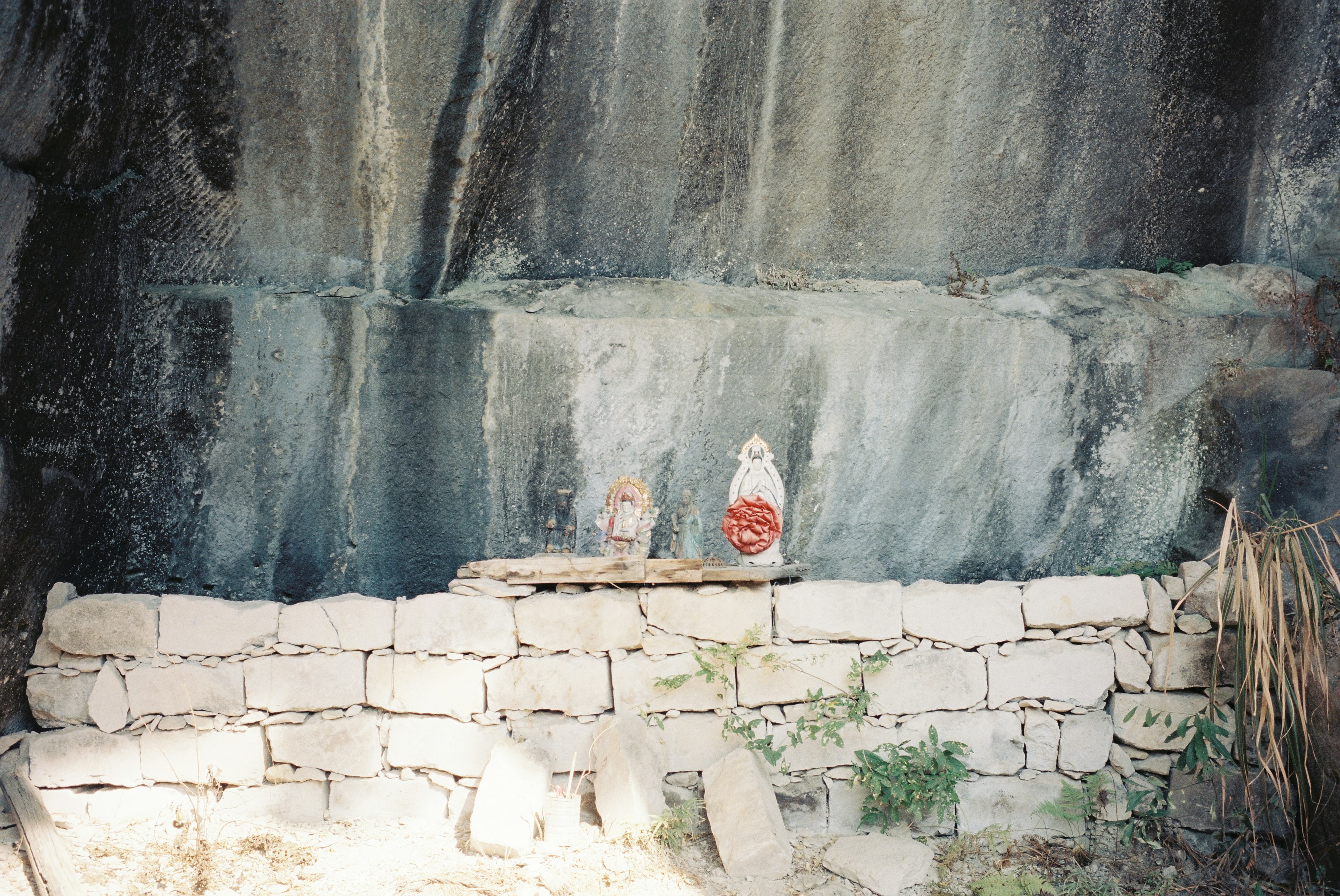 Small figures on a stone wall against a textured rock