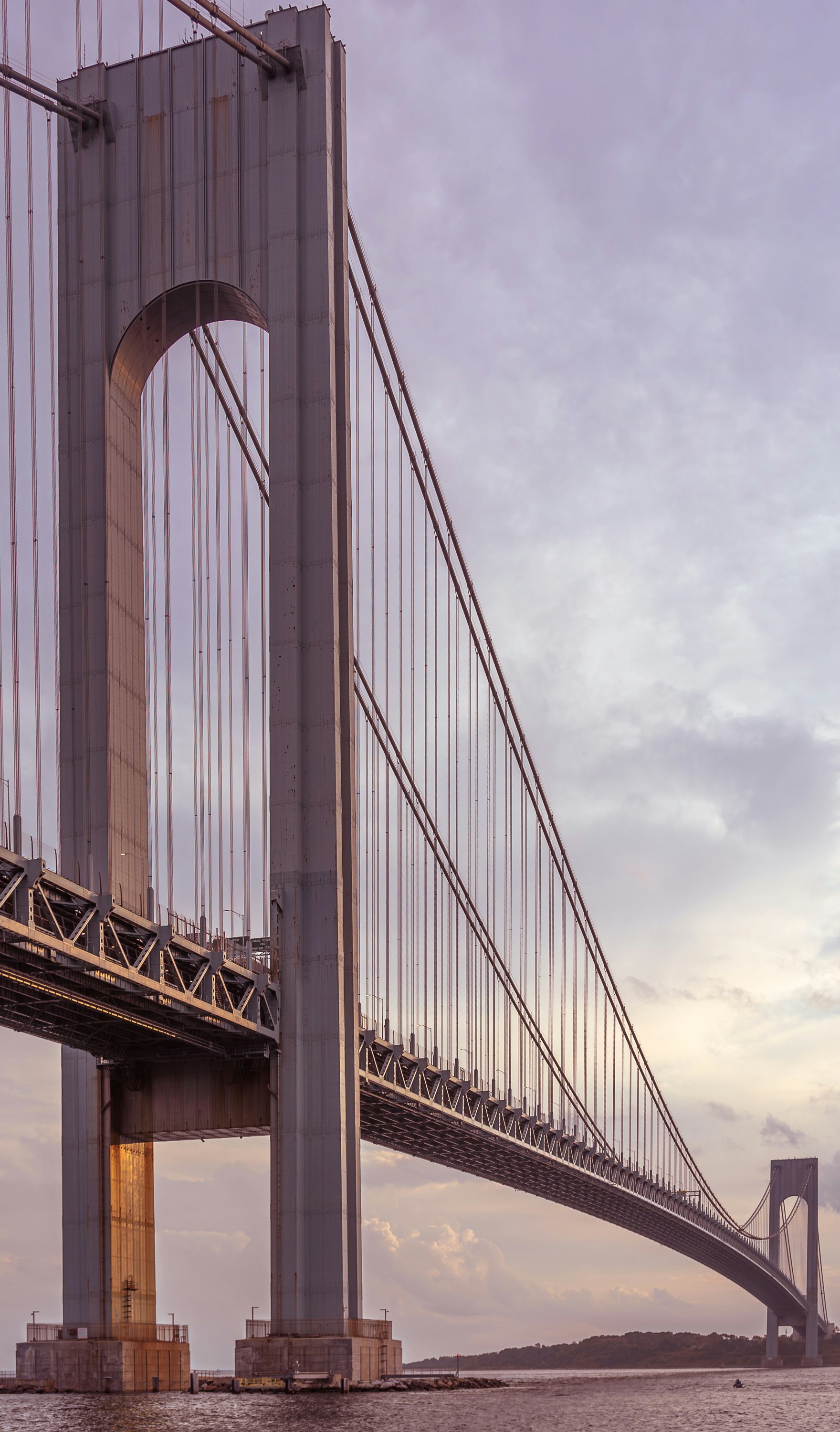 A massive suspension bridge stretches over water at dusk.