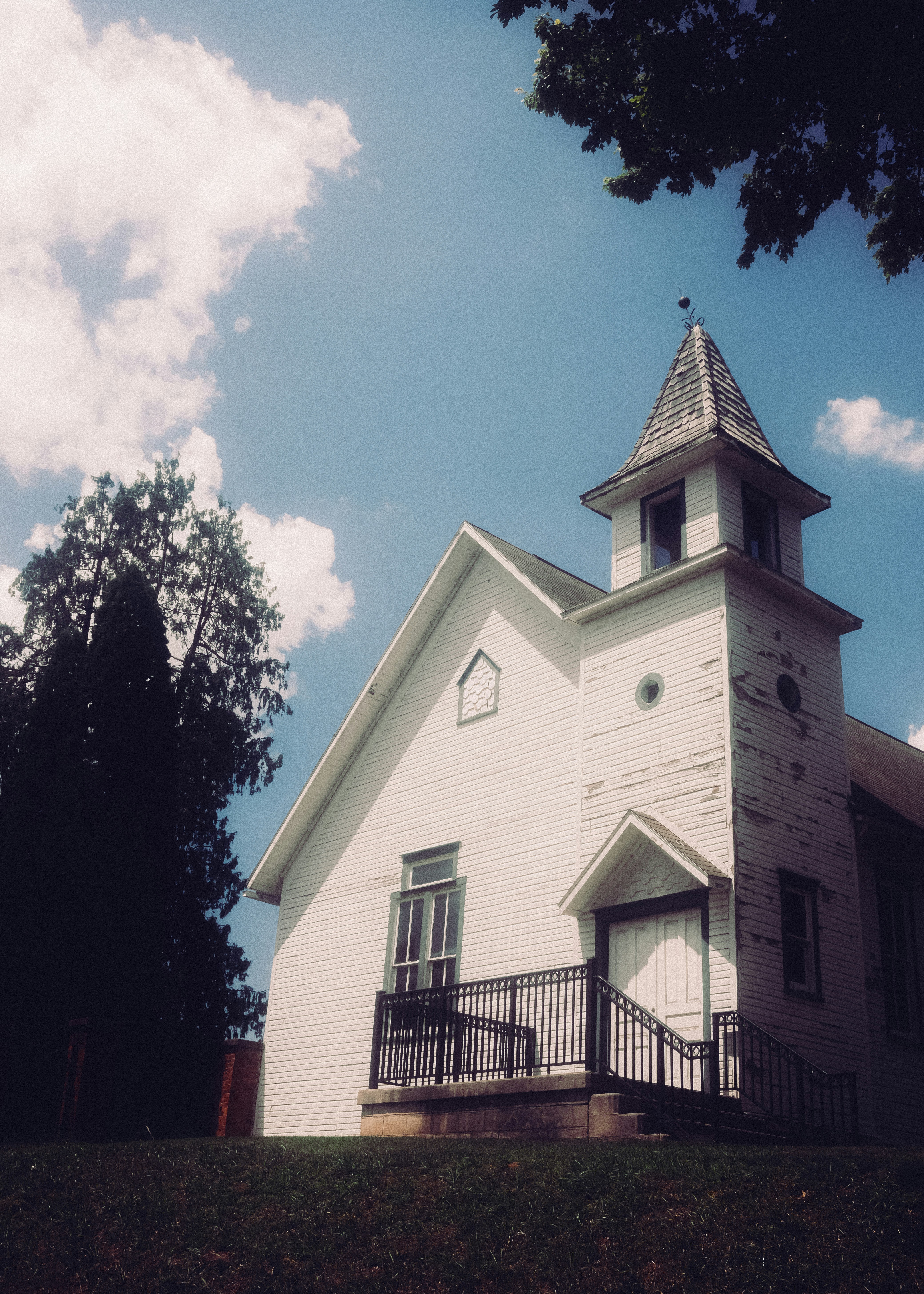 A weathered white church stands against a bright blue sky.