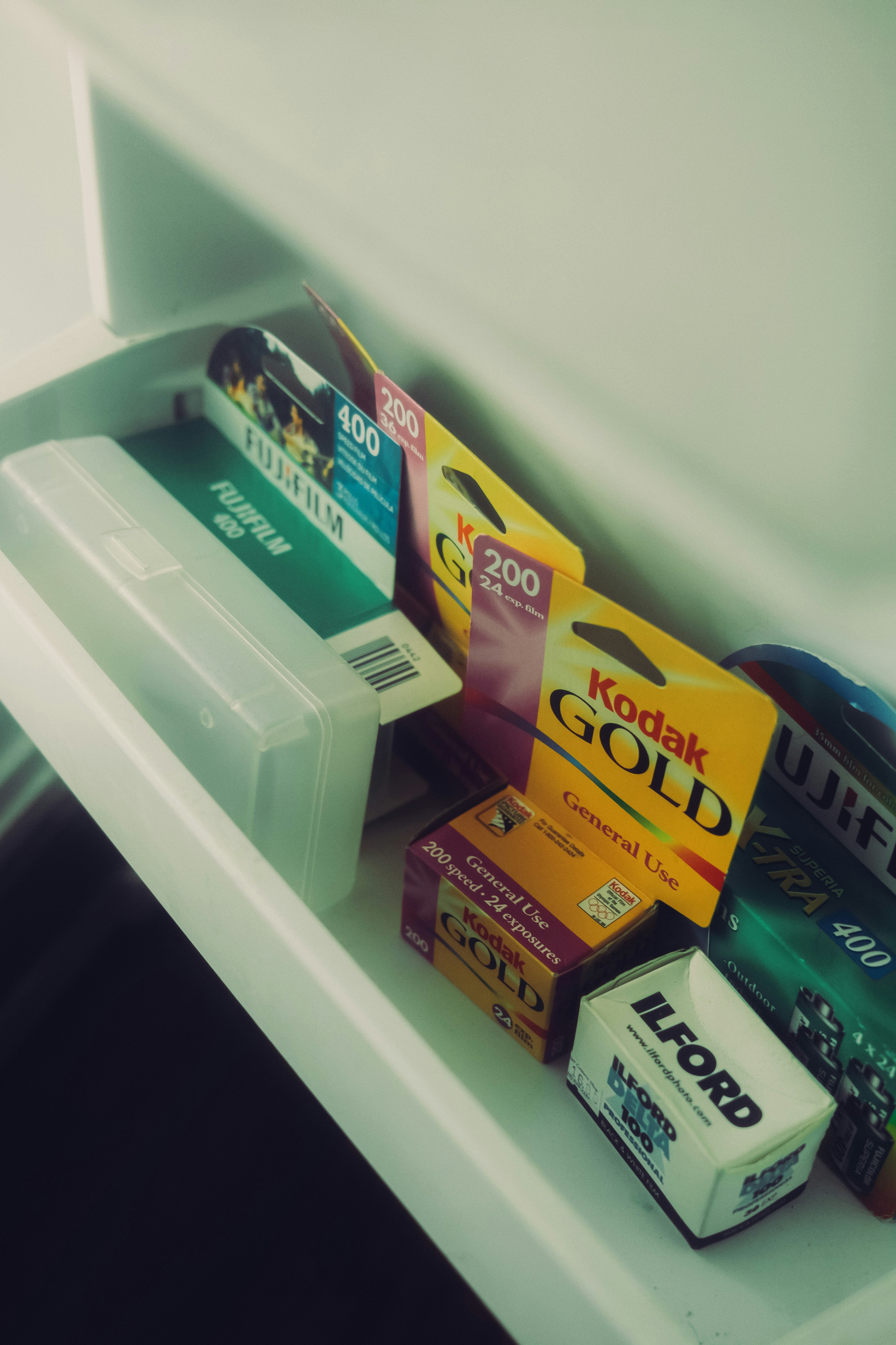Various brands of photographic film rolls stored in a drawer.