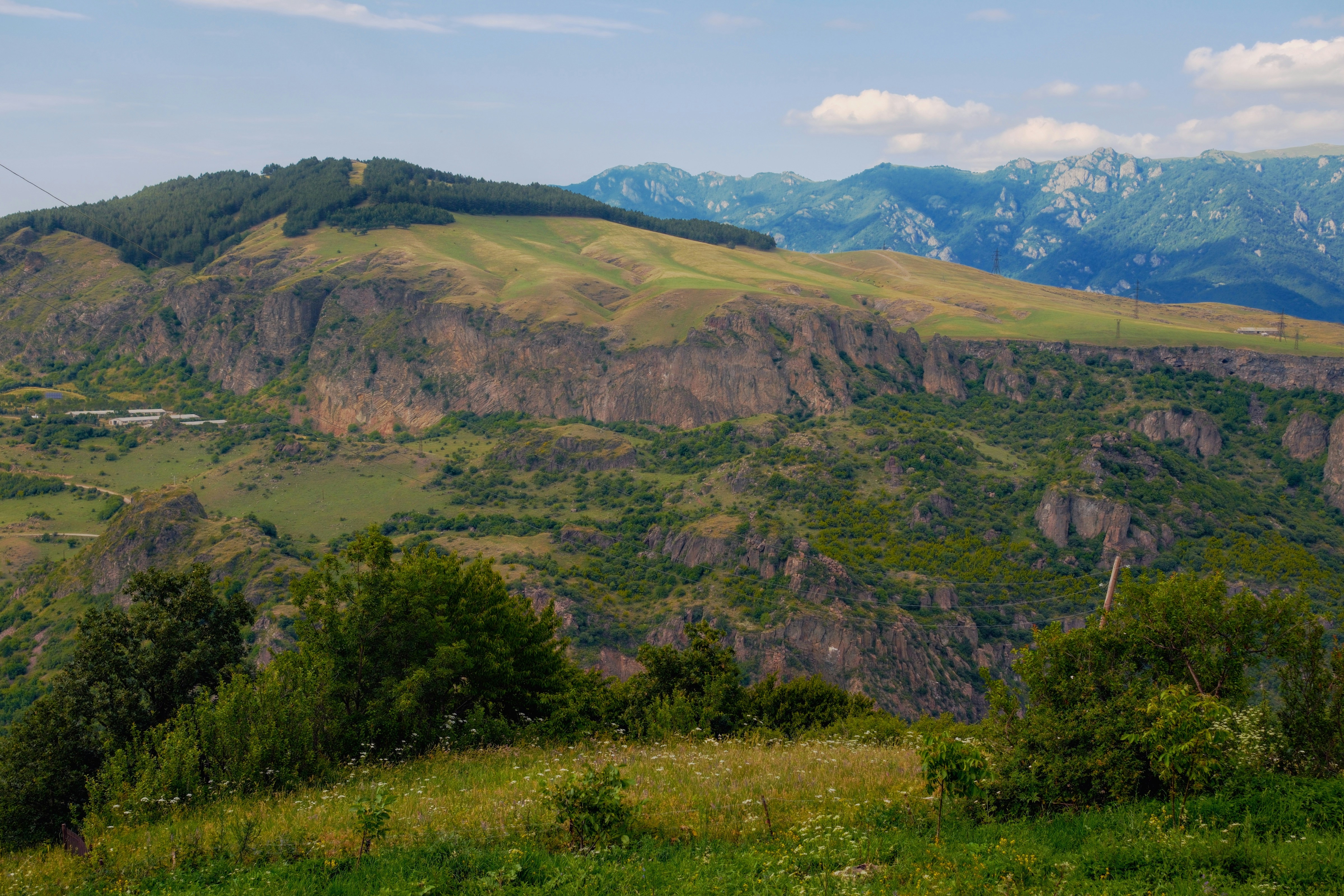 Scenic view of green hills, rocky cliffs, and distant mountains
