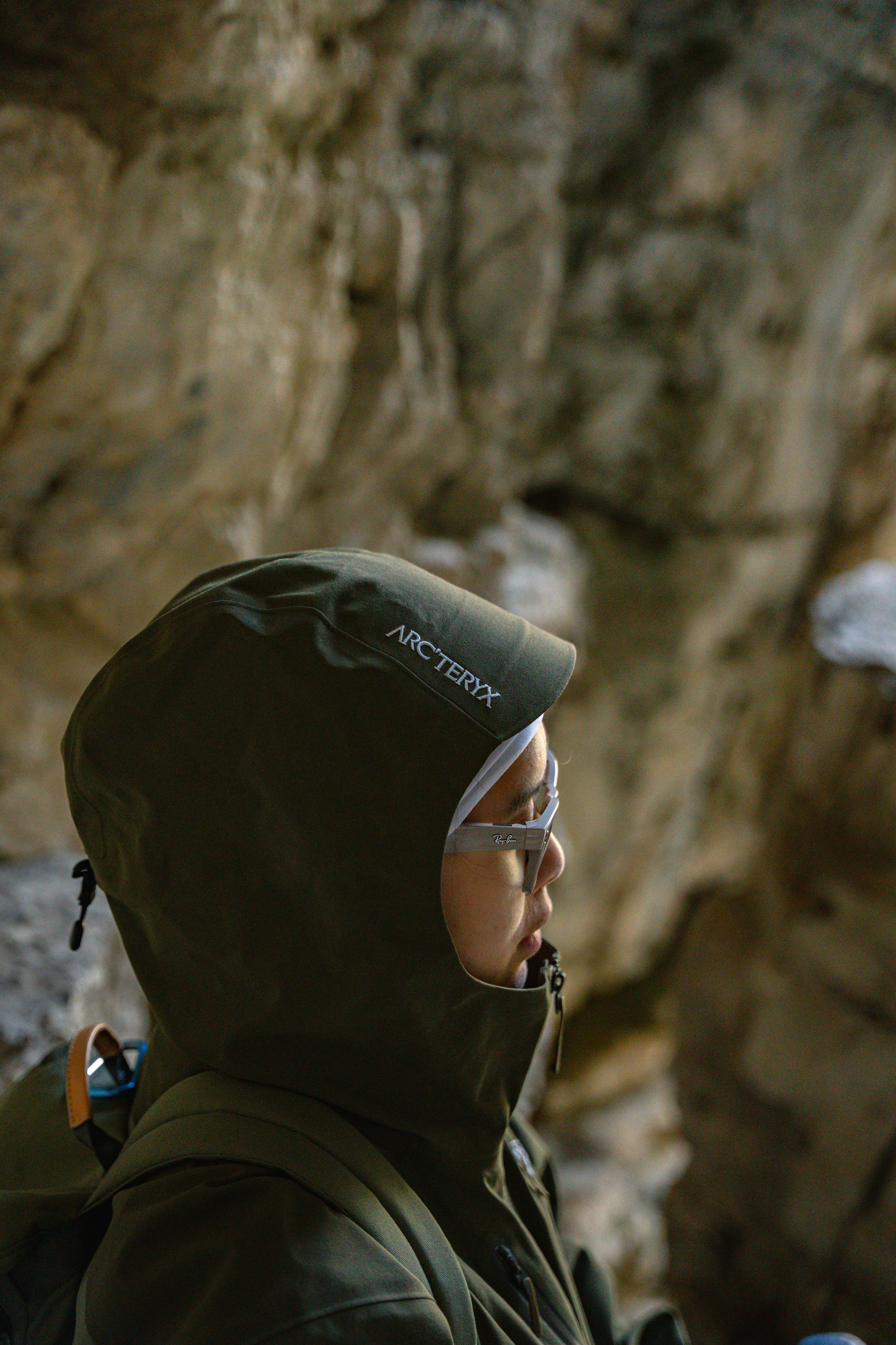 Person in green hooded jacket exploring a rocky cave