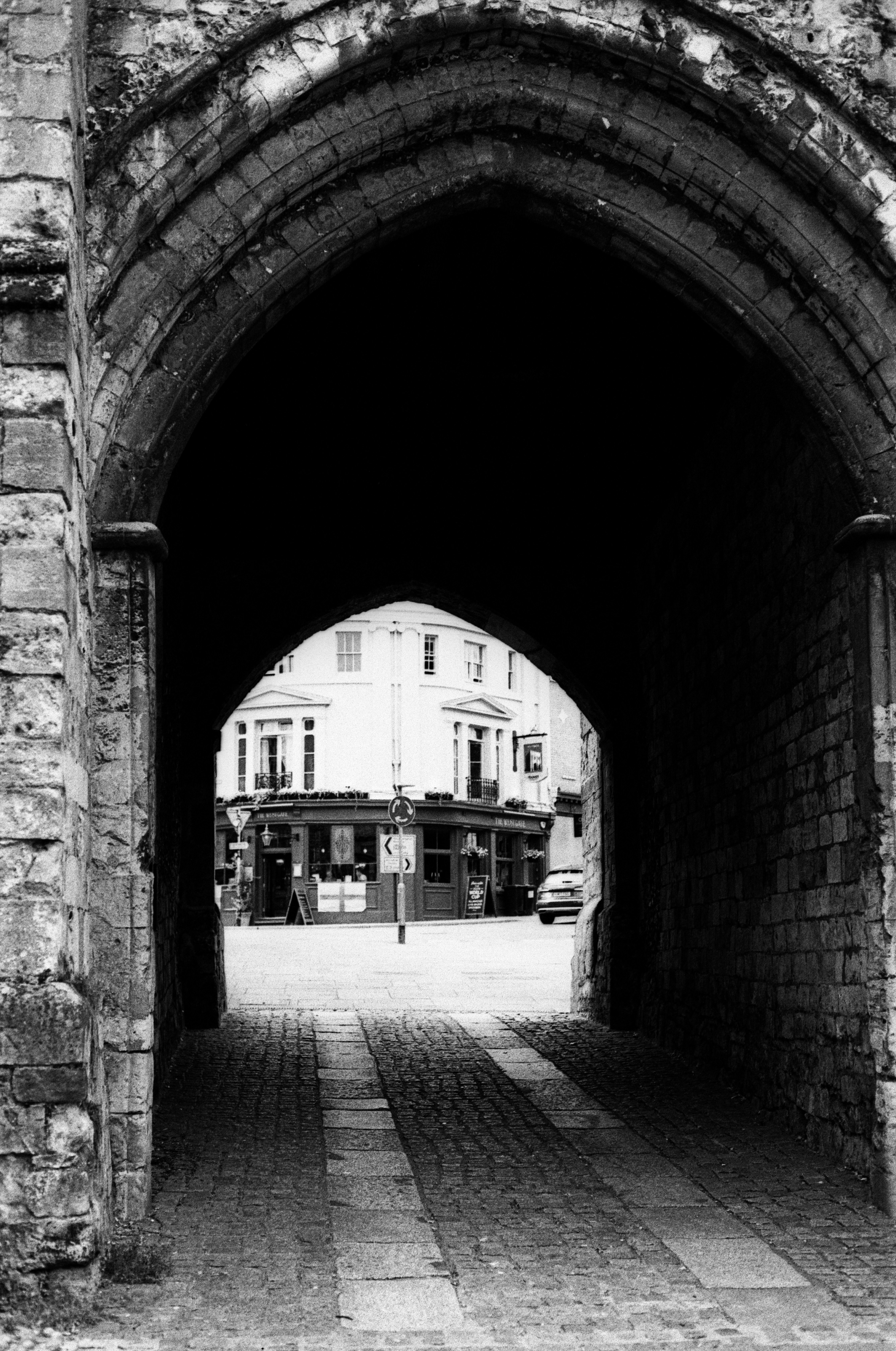 Arco buio che conduce a una luminosa strada cittadina