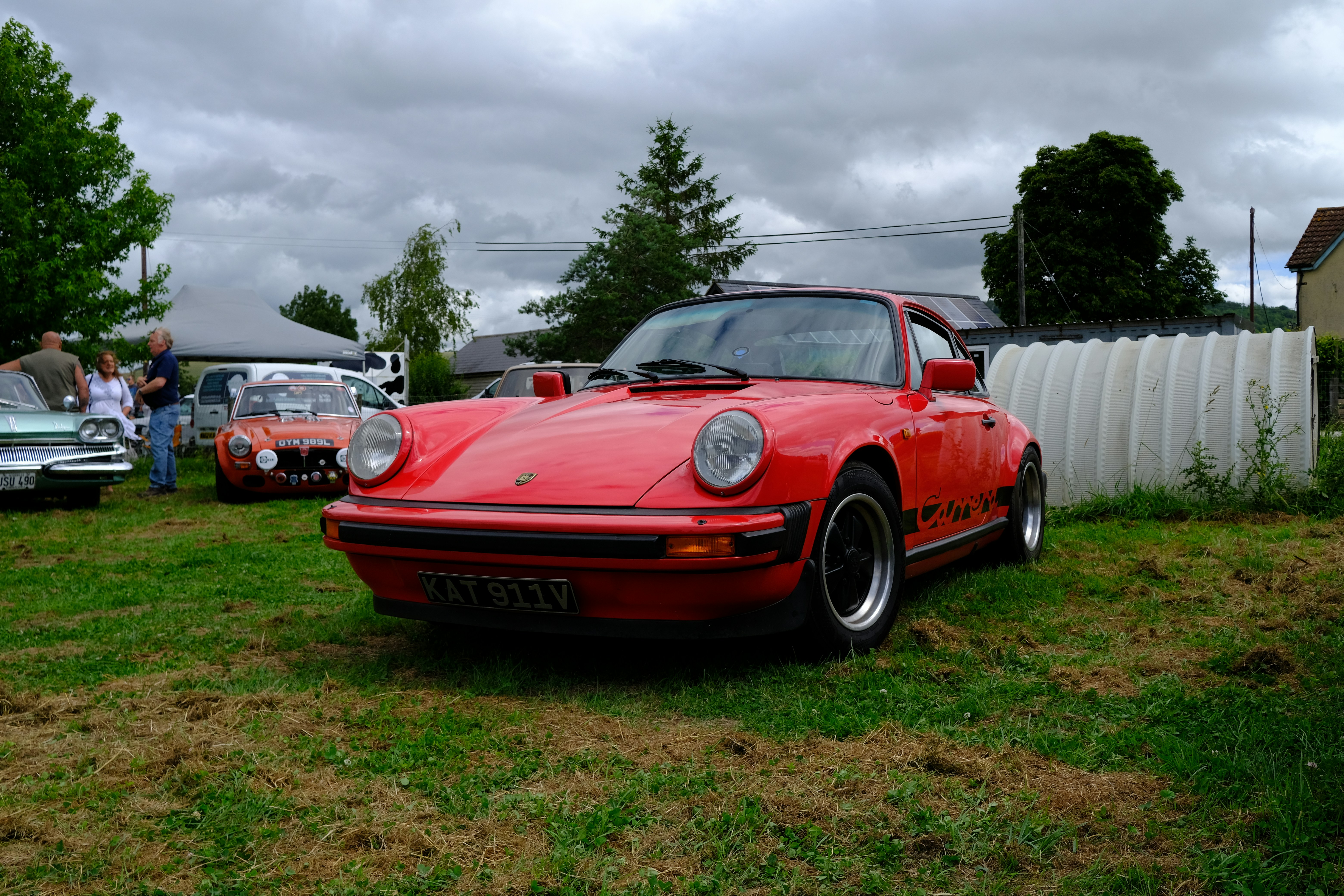 A red classic porsche 911 parked on green grass
