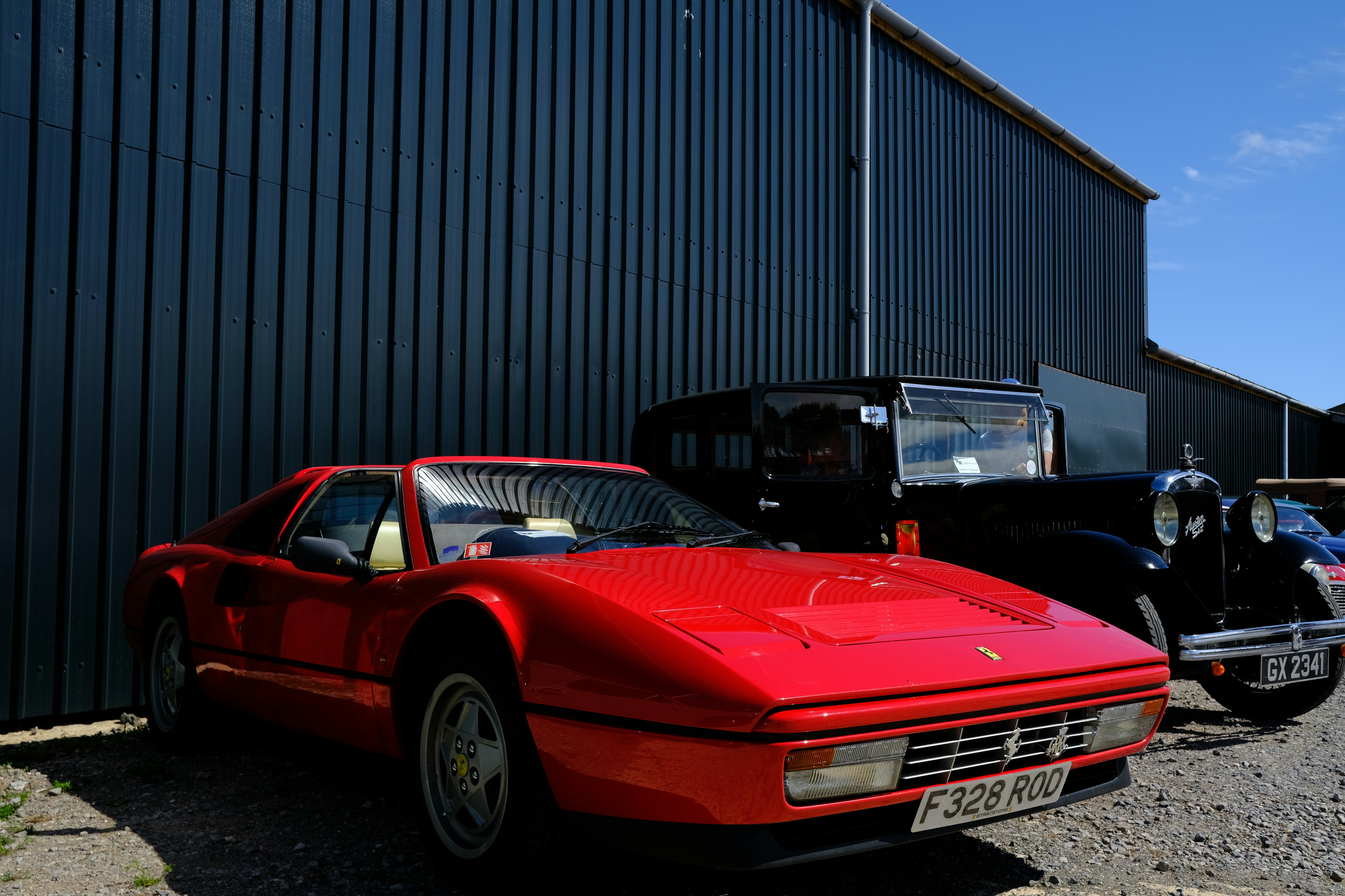 Red ferrari sports car and vintage black car parked outdoors