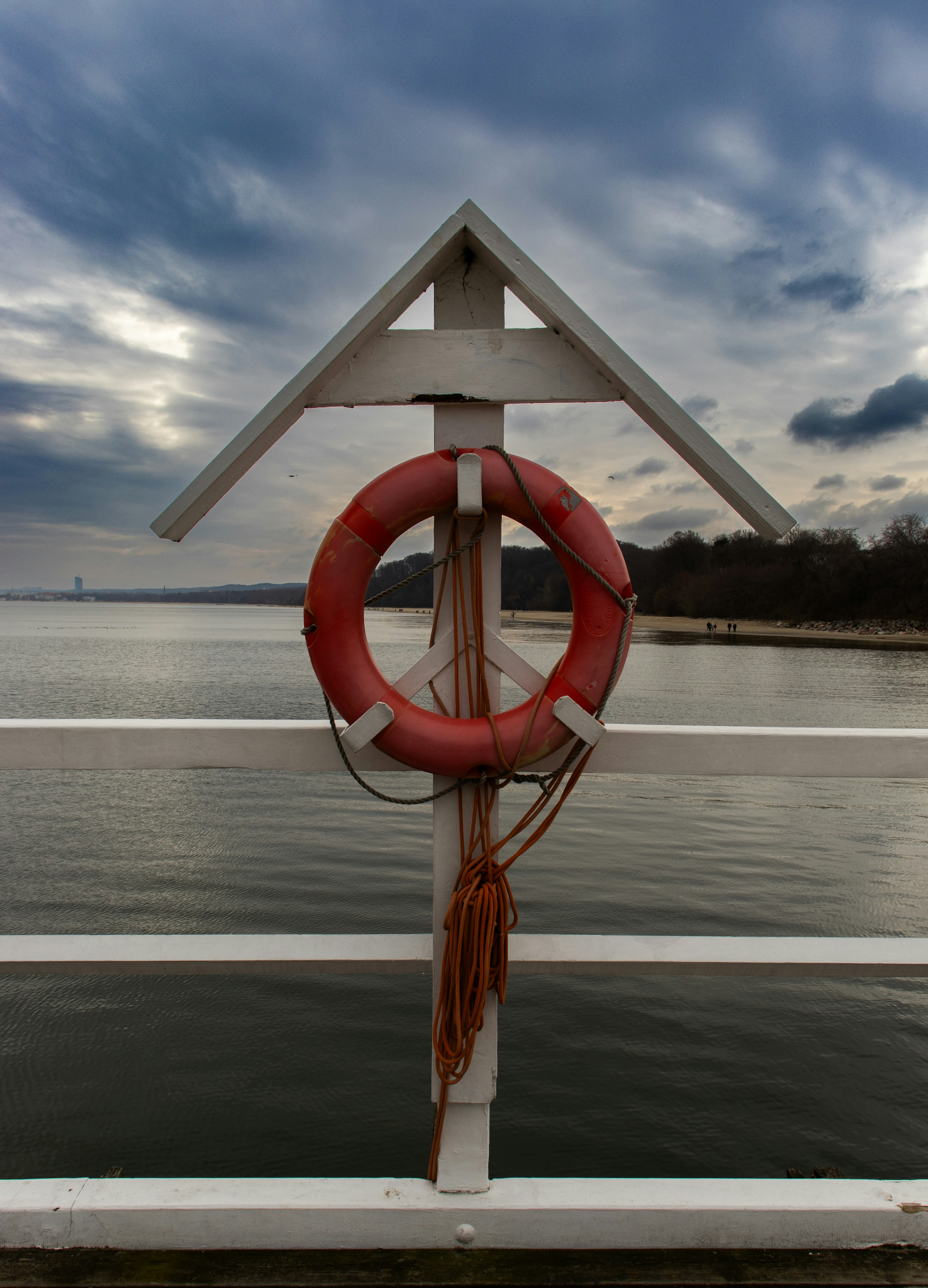 Boia salvavidas roja sobre un poste blanco con vistas al agua.
