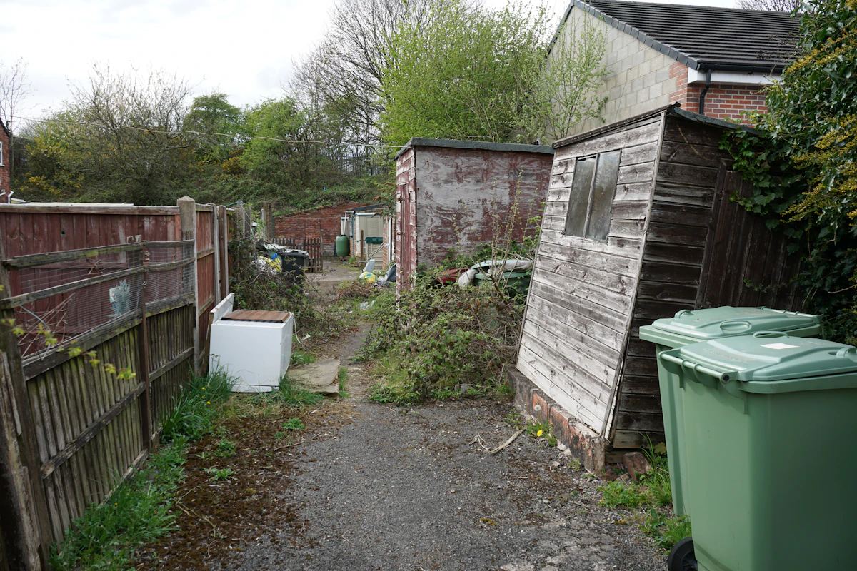 Illustrative starting point: a tired rear garden with old sheds, worn boundaries and an overgrown path