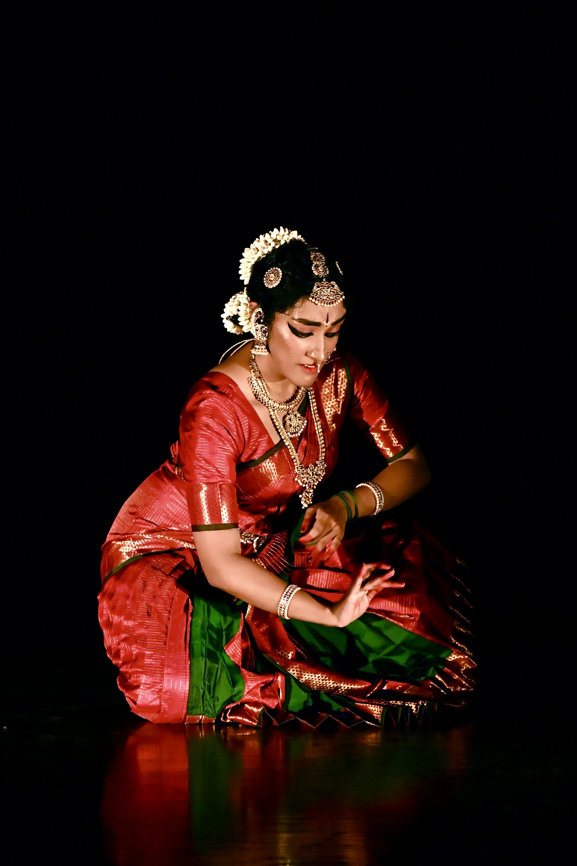Kathak dancer in red costume holding a pose against black