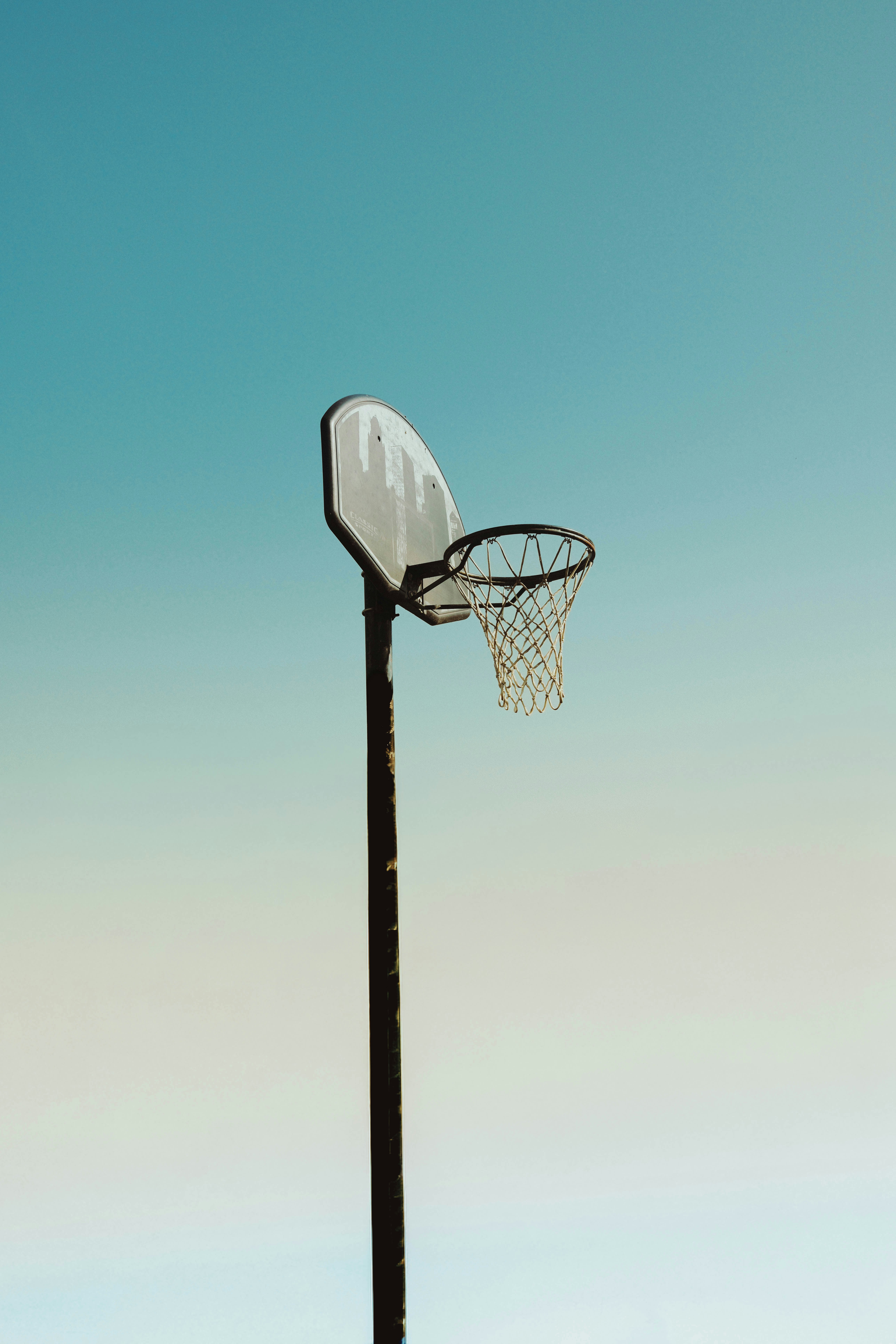 A basketball hoop stands against a clear blue sky.