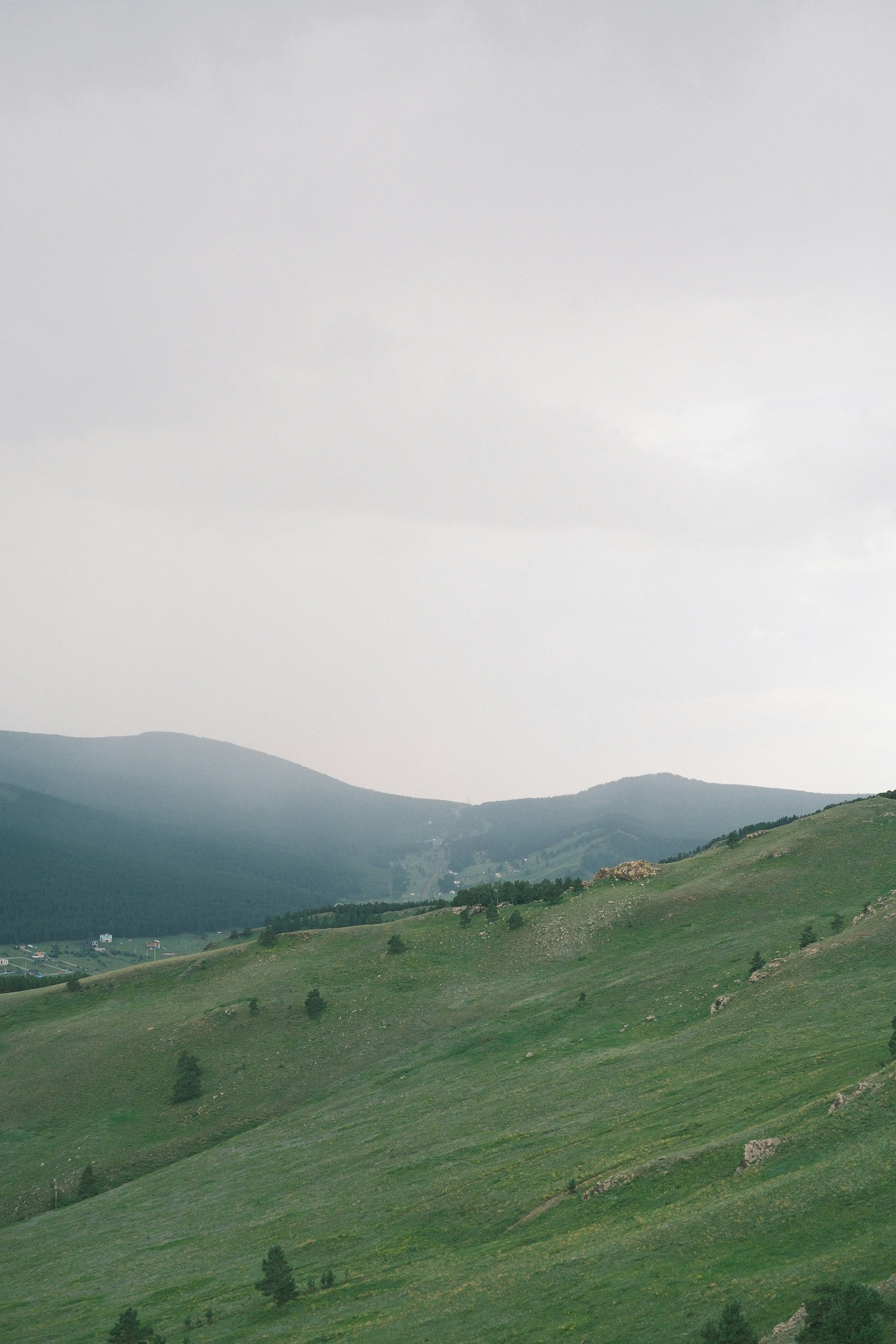 Grüne sanfte Hügel und ferne Berge unter einem bewölkten Himmel
