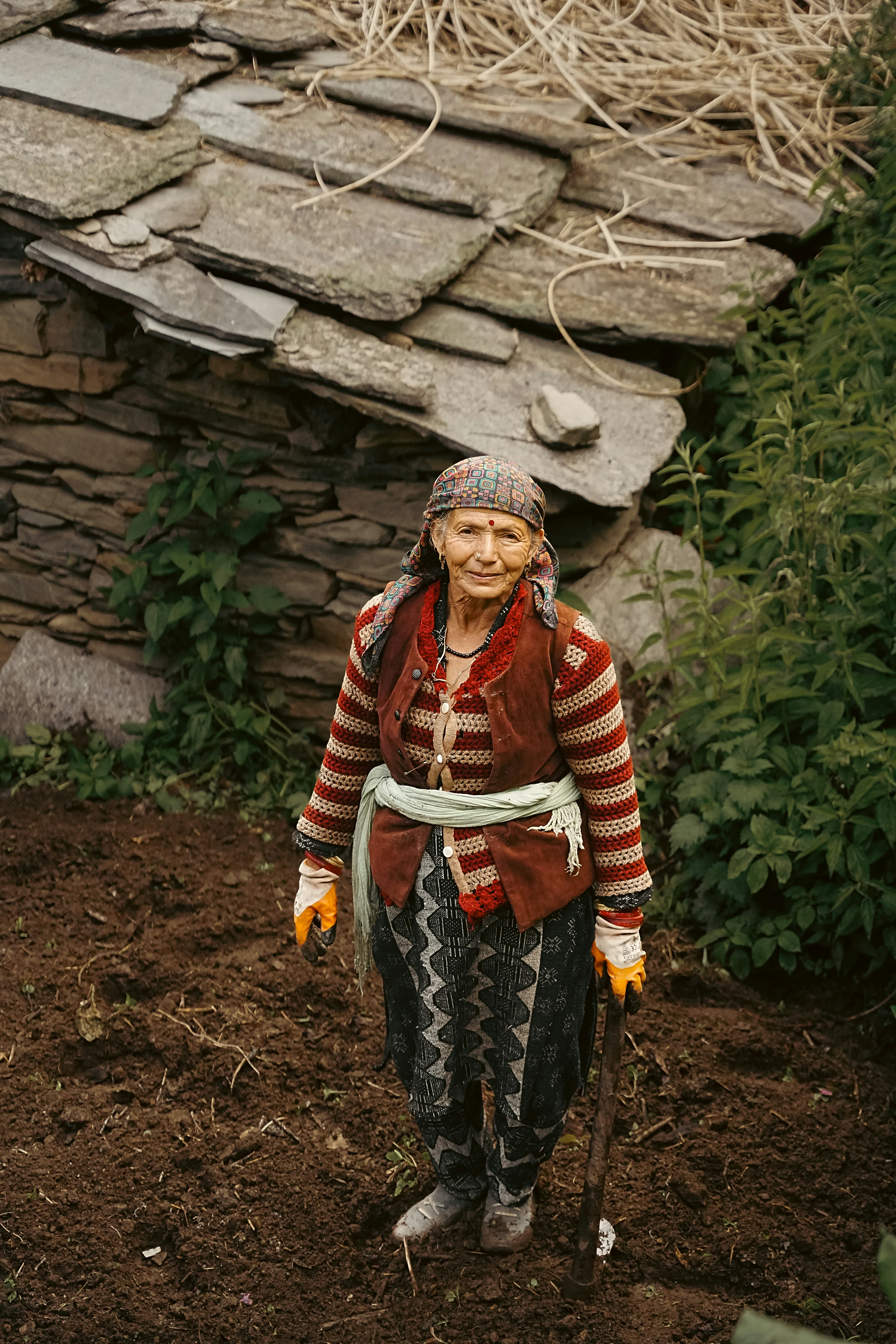Elderly woman in traditional clothes stands in a garden