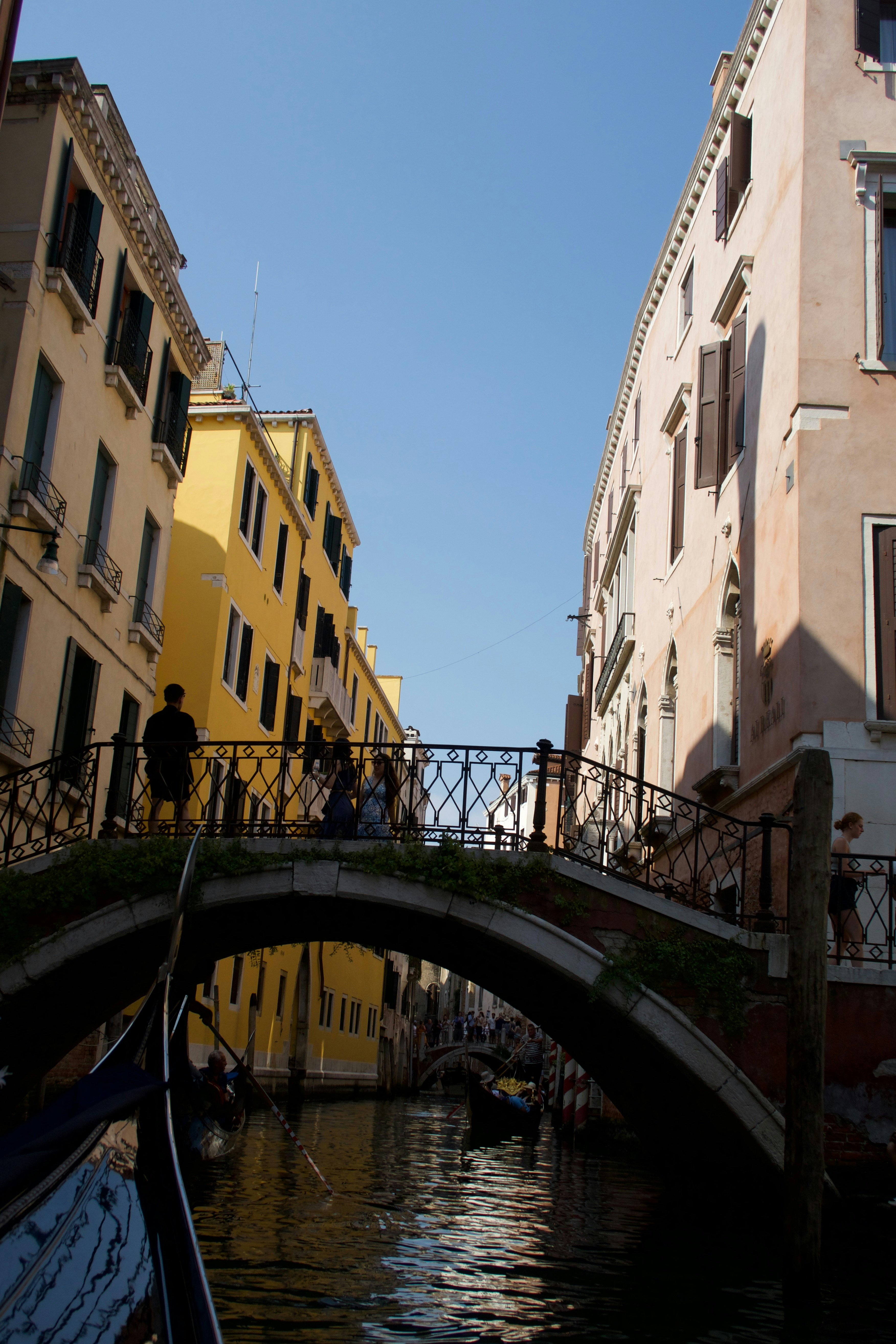 Ein venezianischer Kanal mit einer Brücke, historischen Gebäuden und Menschen.