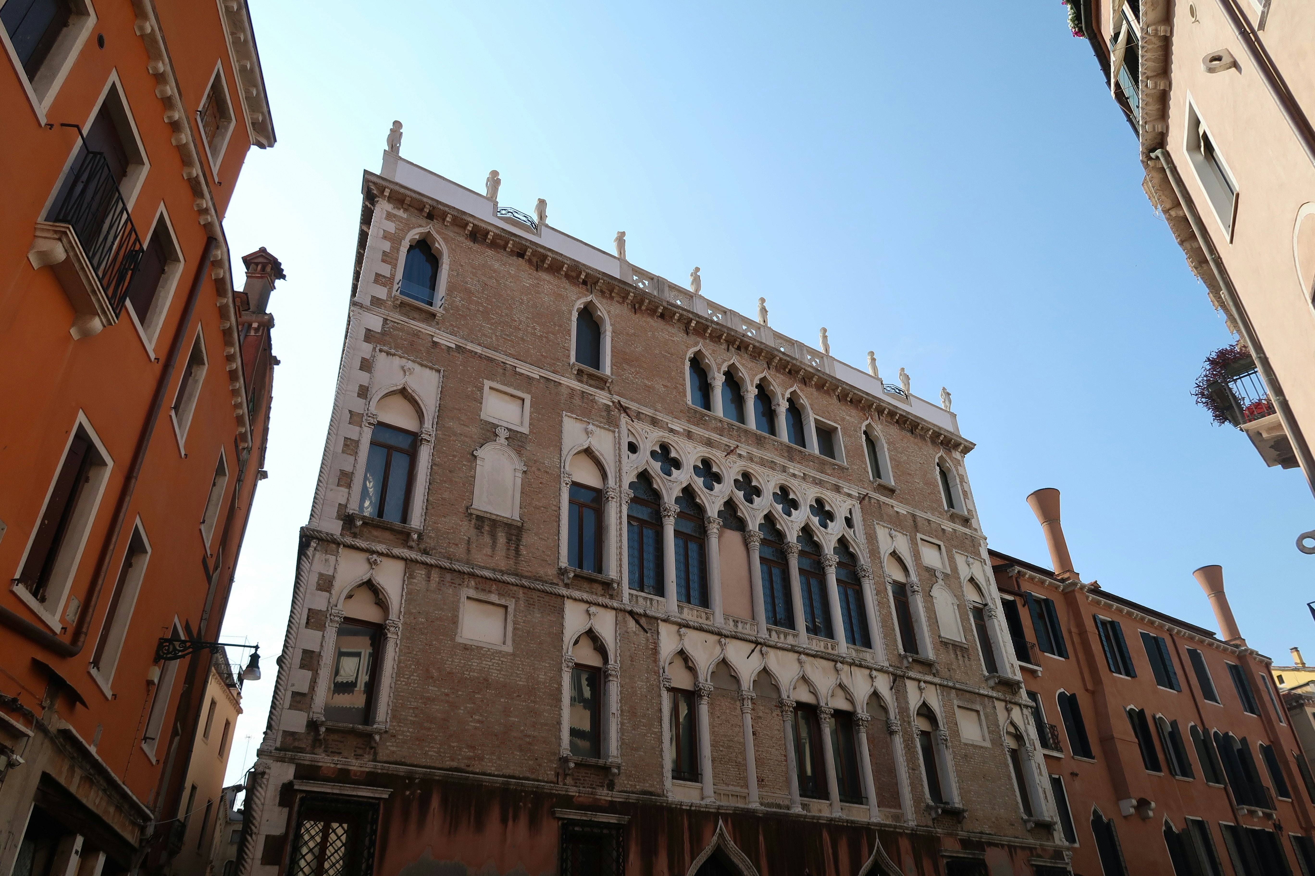 Historisches venezianisches Gebäude mit kunstvollen Fenstern unter klarem Himmel.