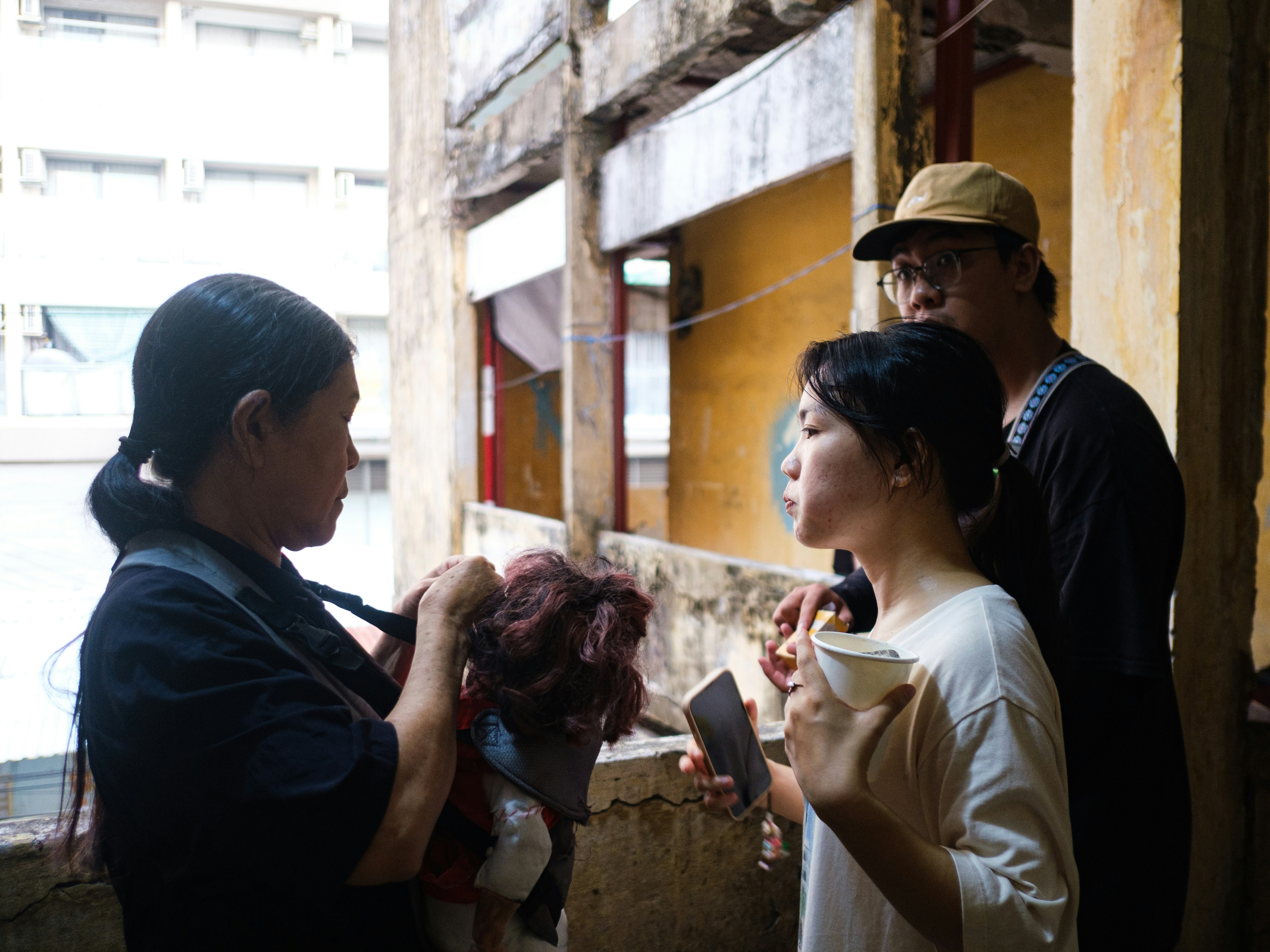 Three people talking on an old building's balcony.