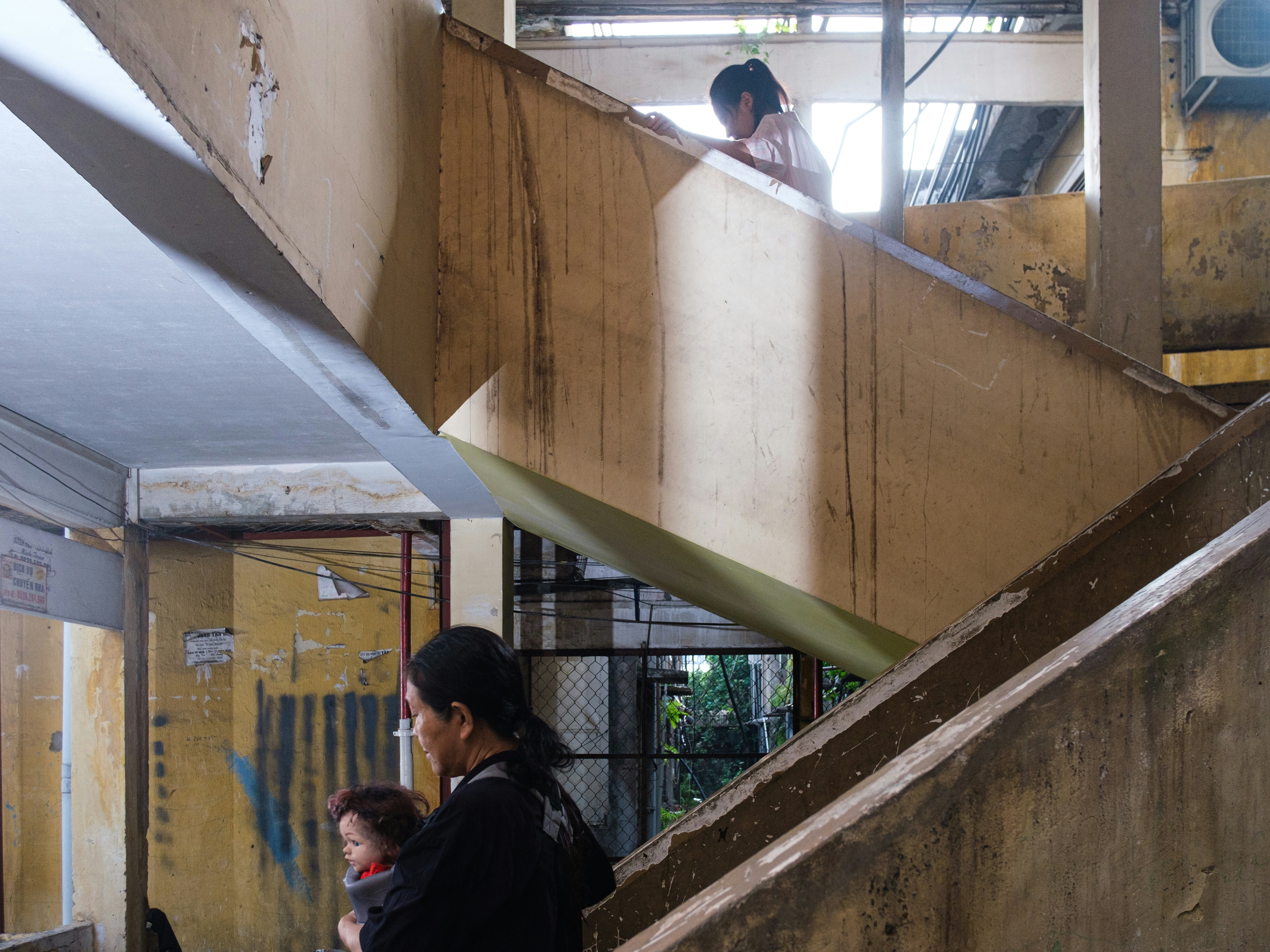 A woman with a baby and child on concrete stairs.