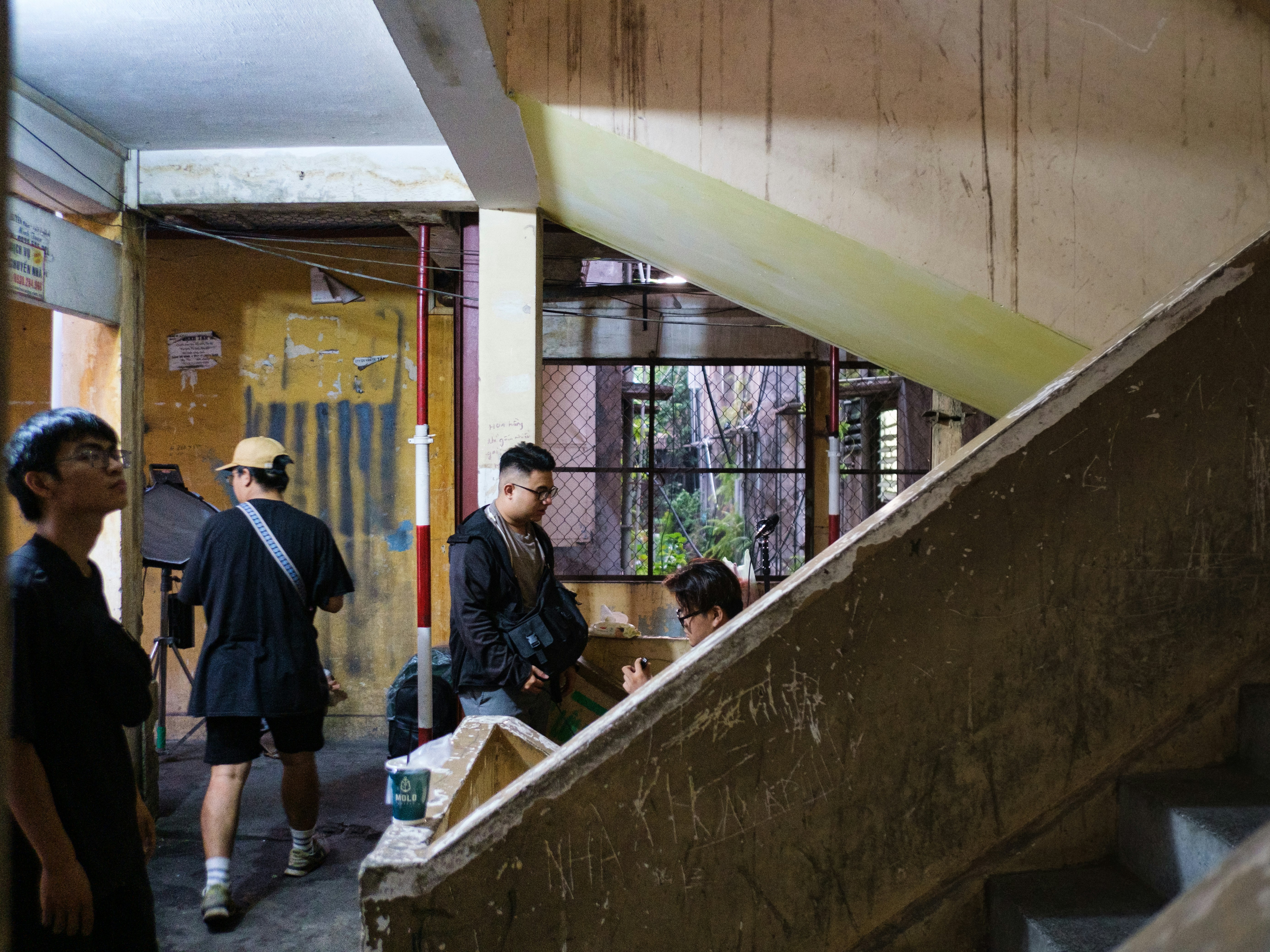 Persone in piedi in un vecchio edificio fatiscente con scale.