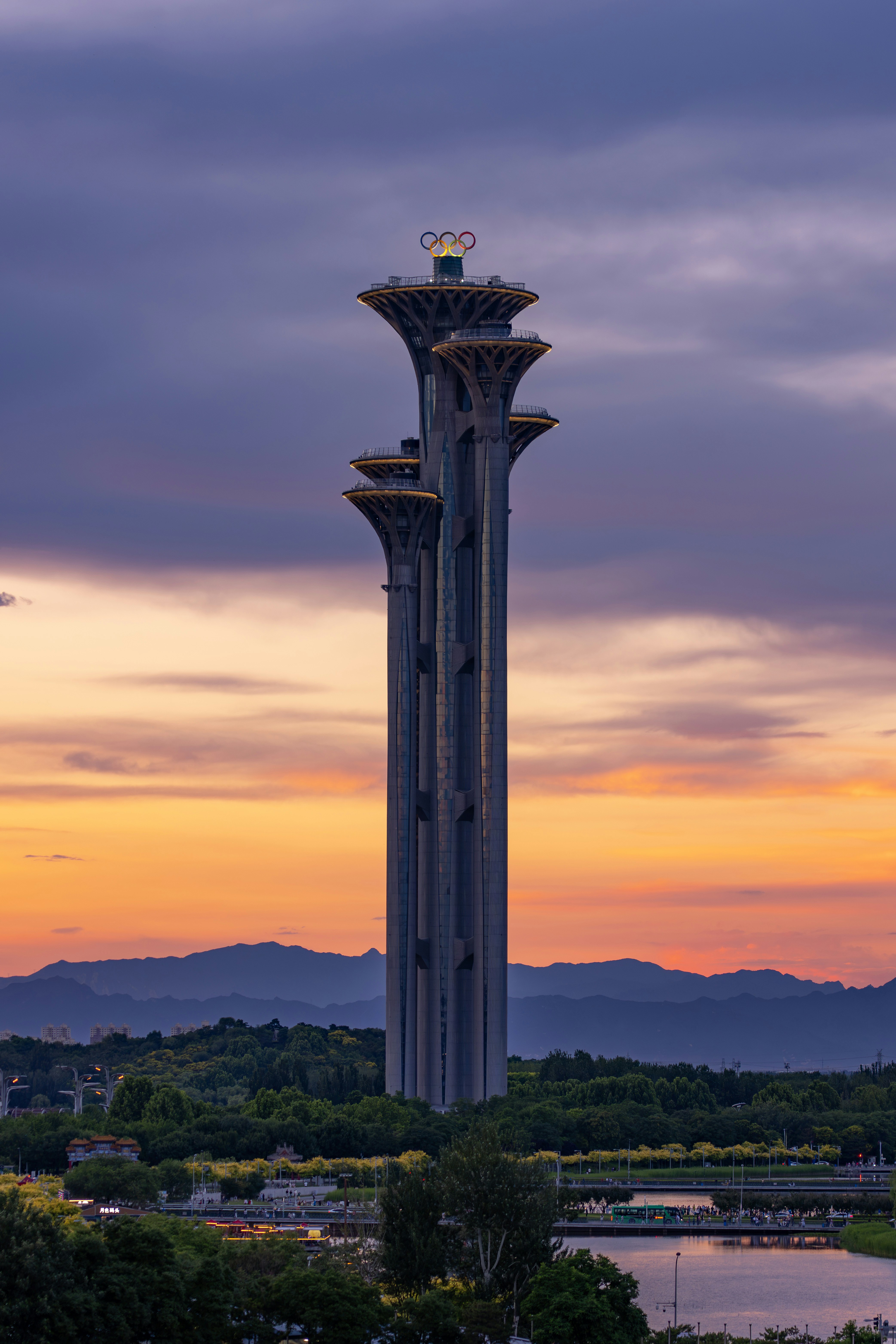 Beijing olympic tower at sunset with vibrant sky and mountains.