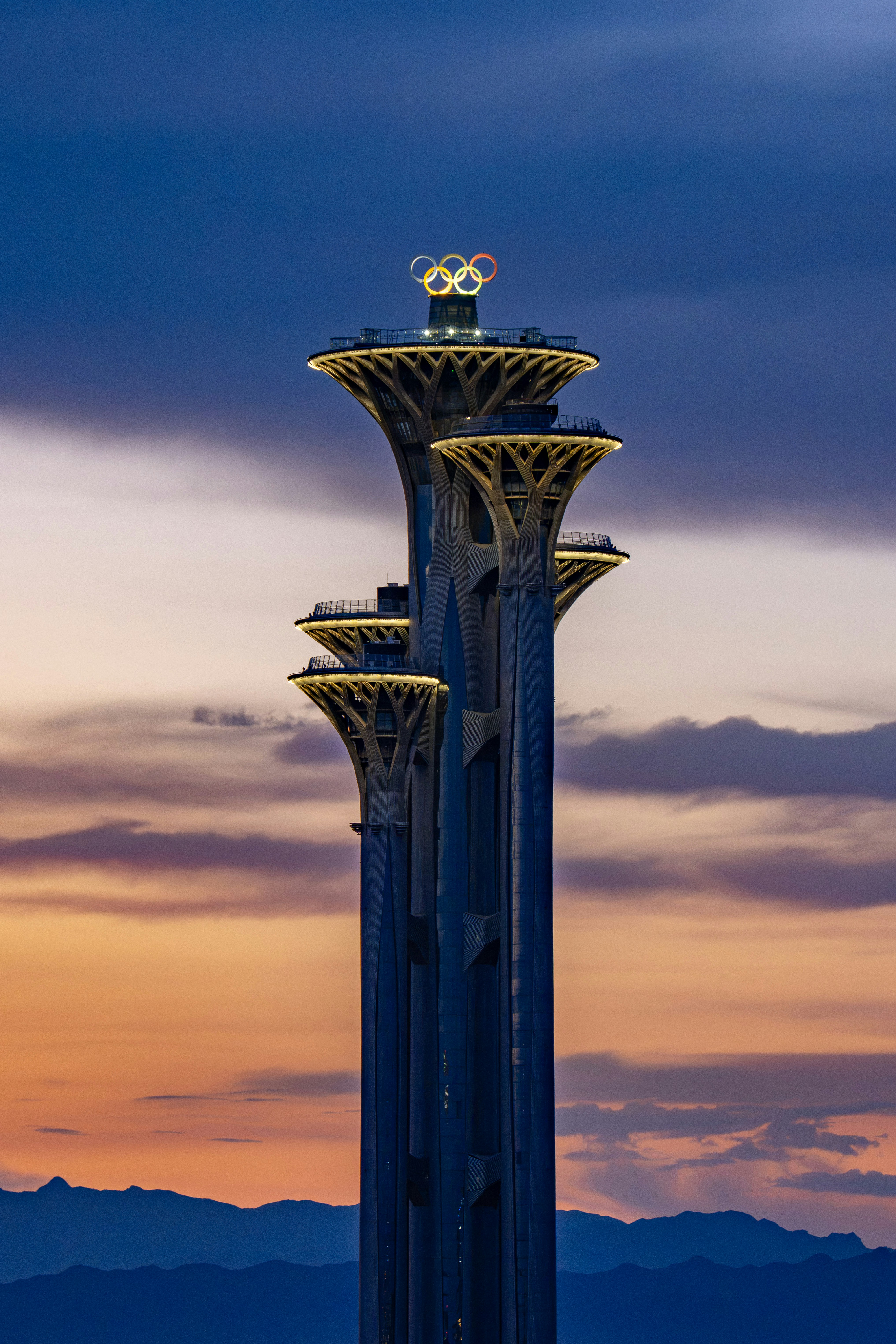 Beijing olympic tower illuminated against a vibrant sunset sky.