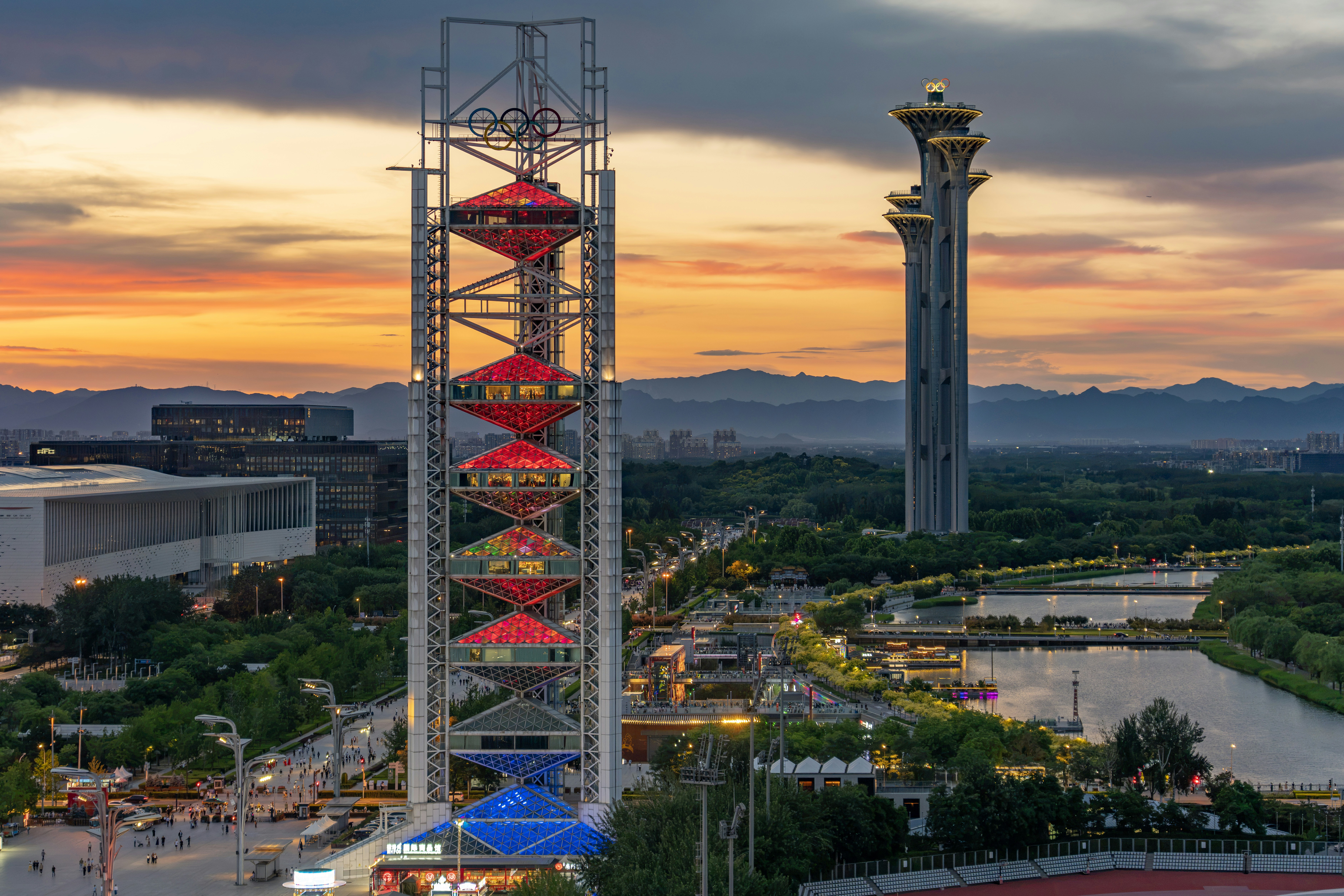 Illuminated beijing olympic tower and city skyline at sunset.