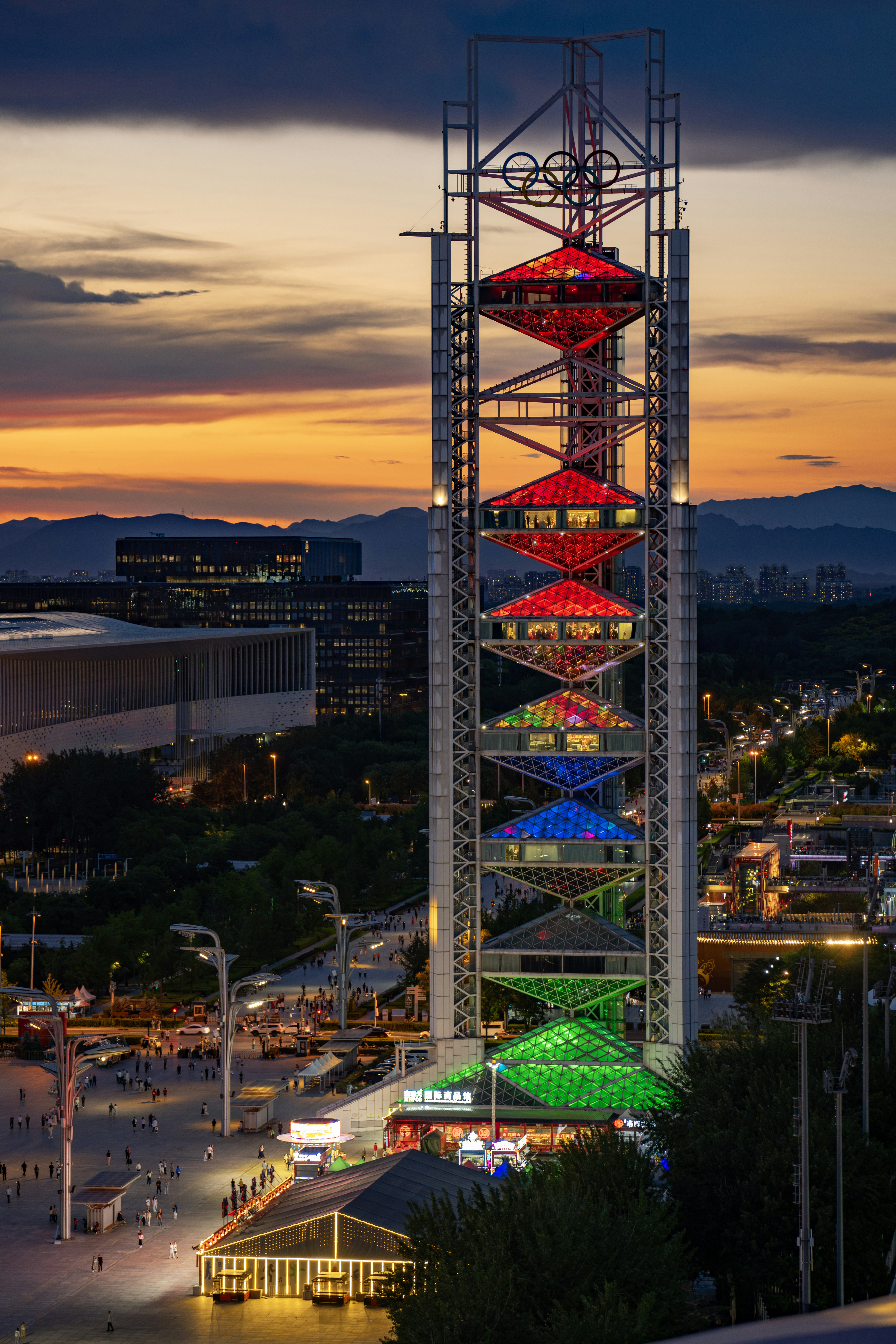 Tall illuminated tower with colorful lights against a sunset sky.