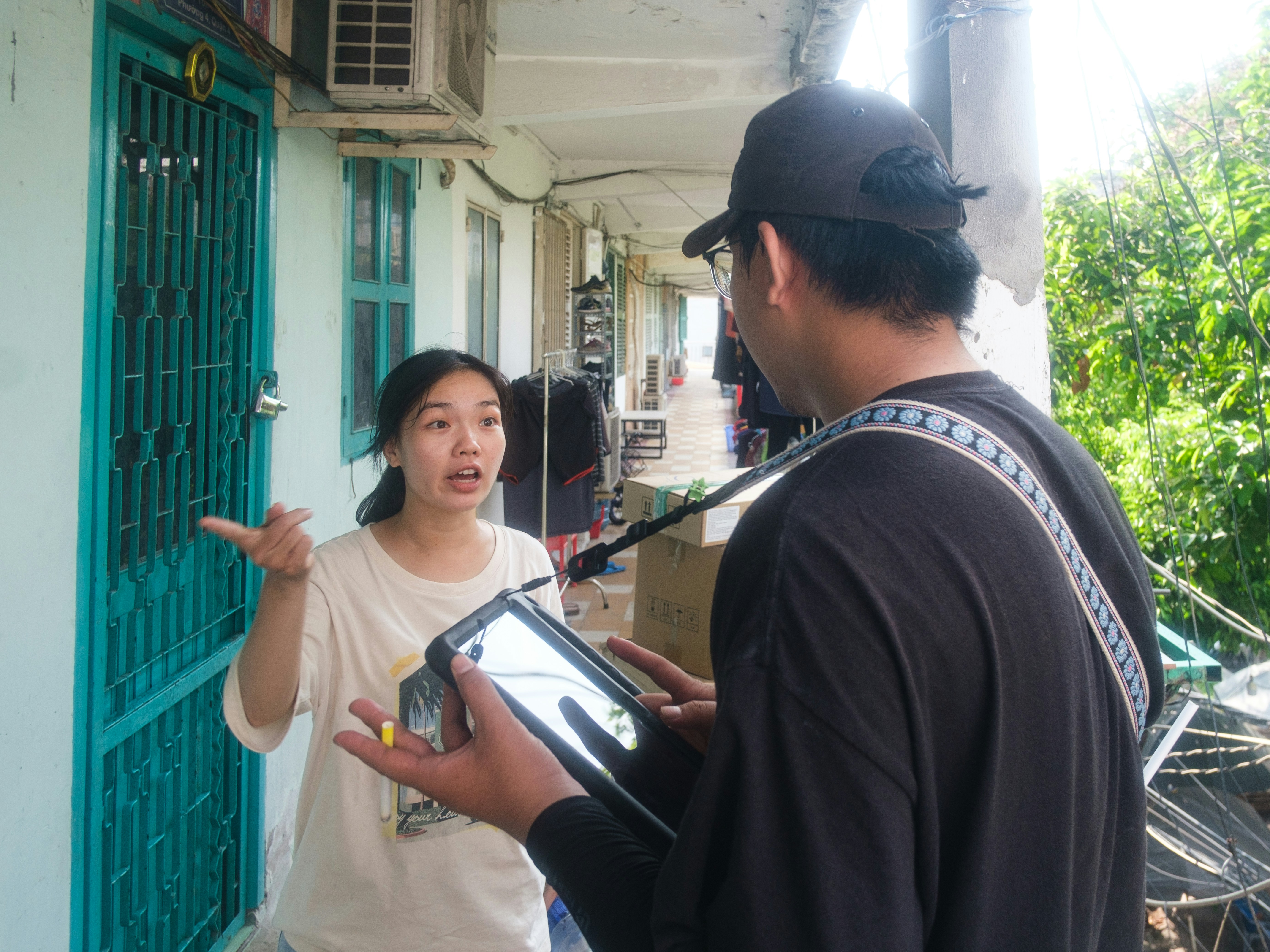 A woman talks to a man holding a tablet outdoors.