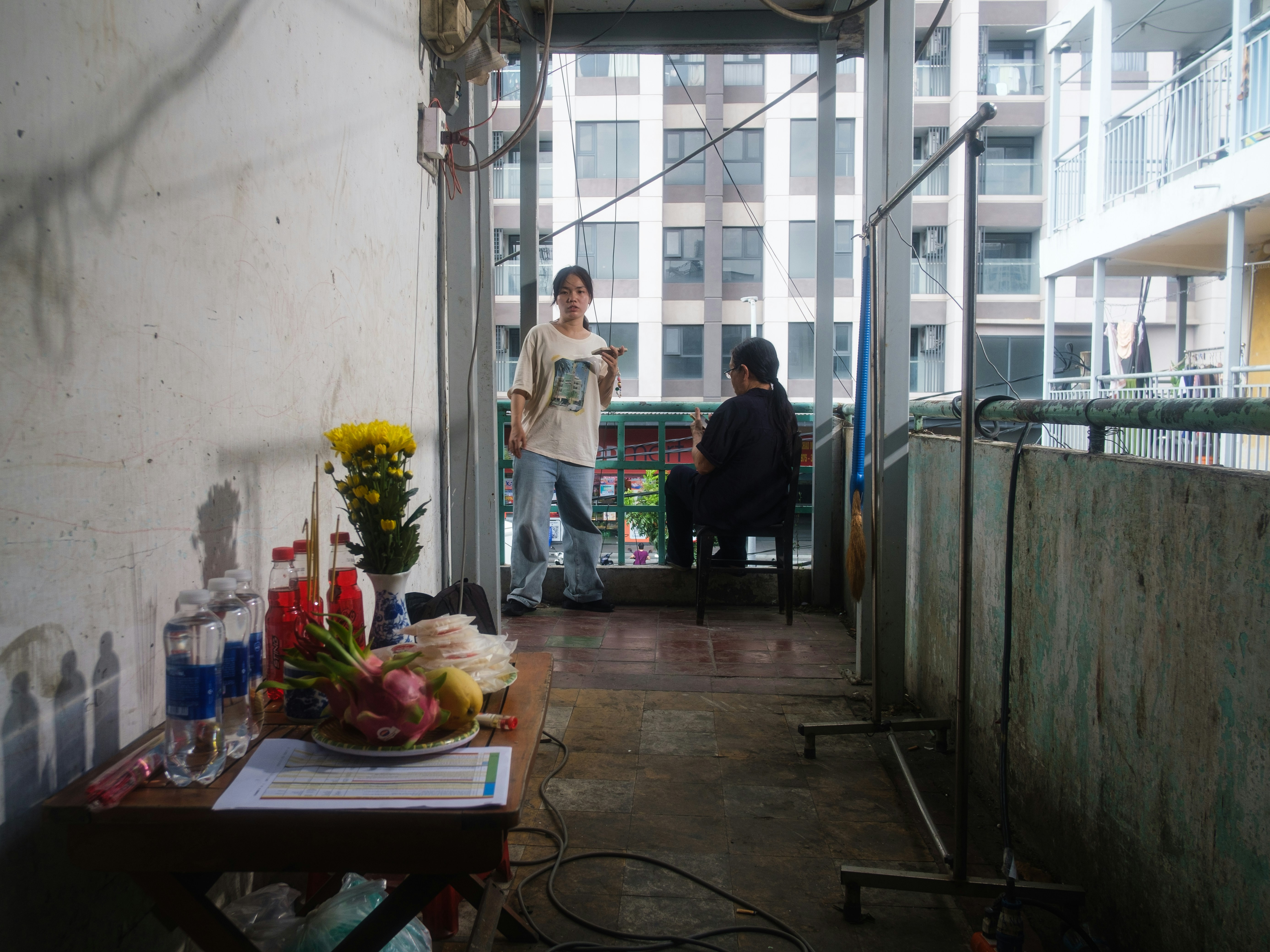 Dua orang bercakap-cakap di balkon perkotaan yang sempit dengan persembahan.