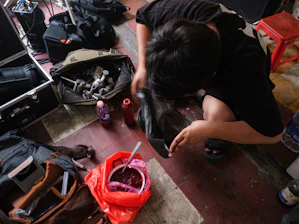 Person on floor surrounded by bags and a red container.