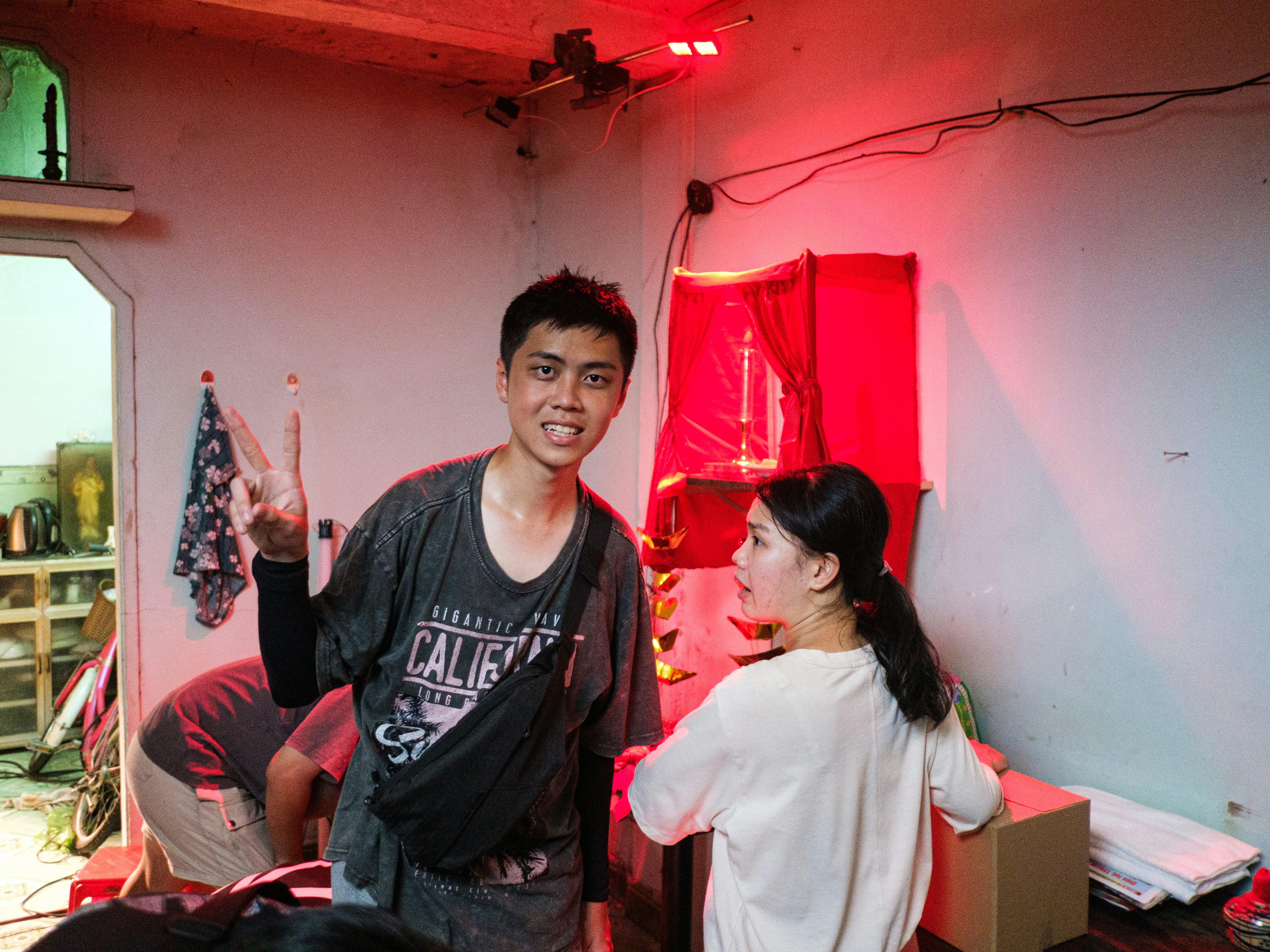 A man makes a peace sign in a red-lit room