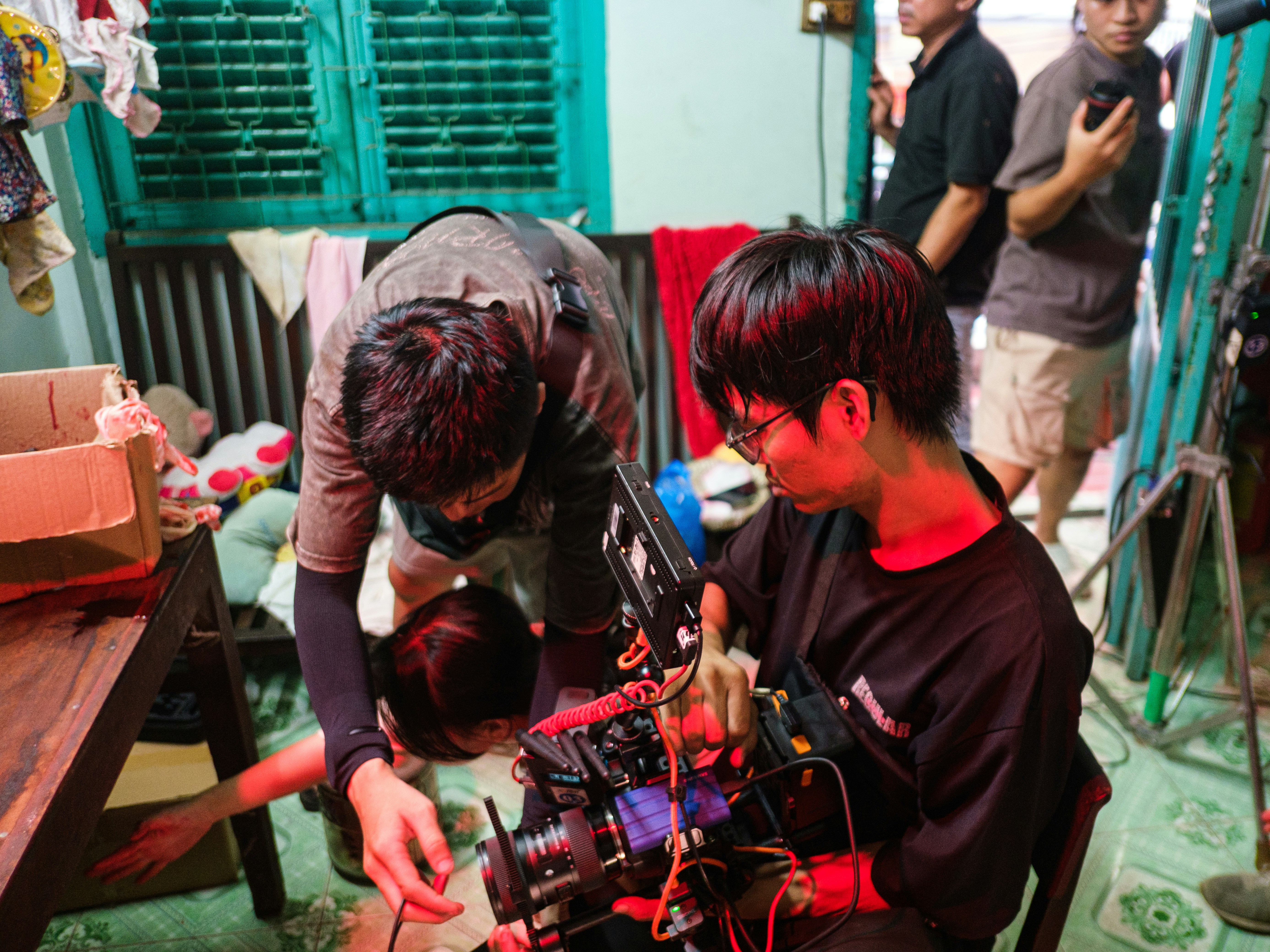 Filmmakers meticulously adjusting professional camera equipment indoors.