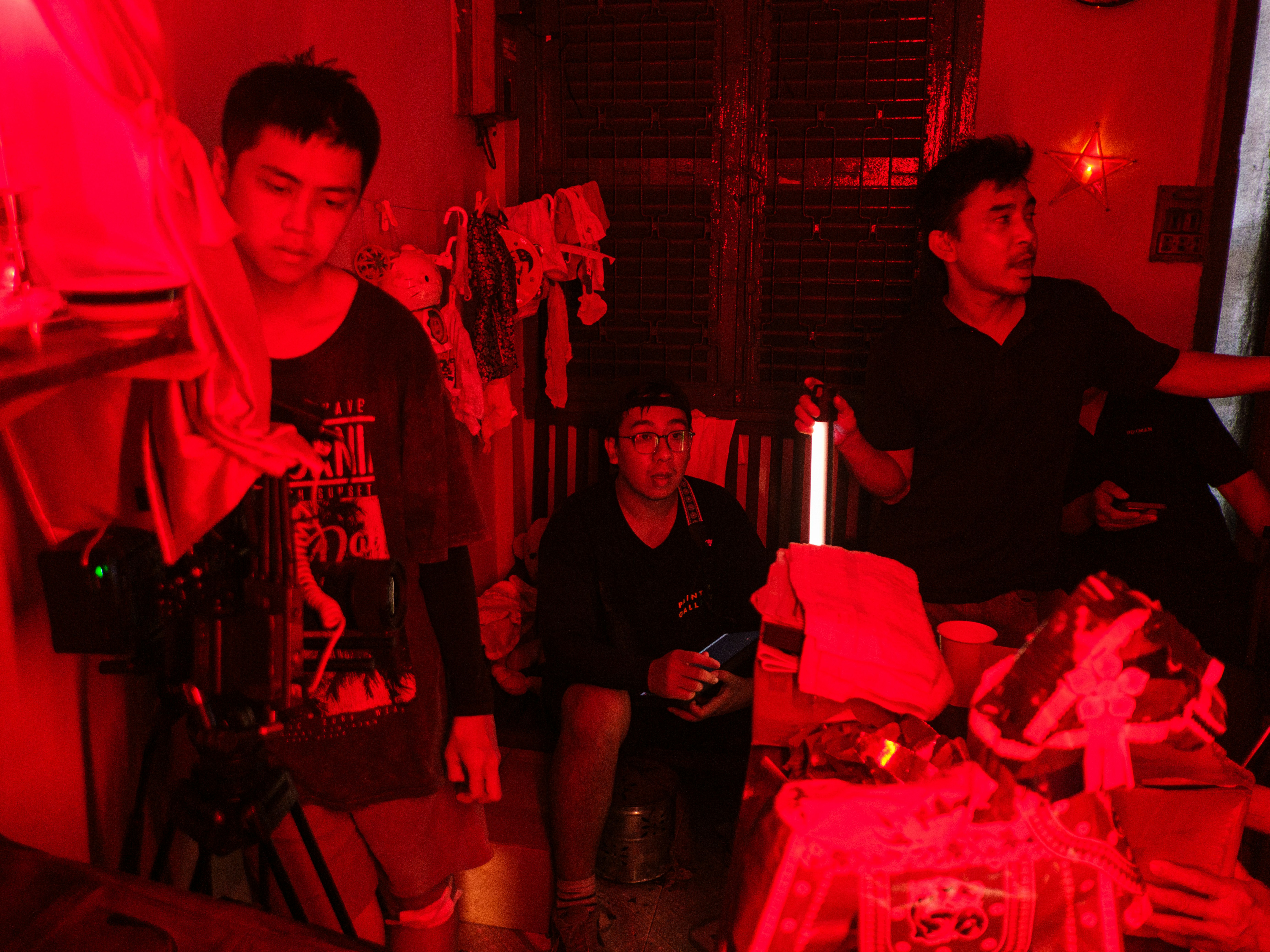 Three men in a red room with a glowing stick
