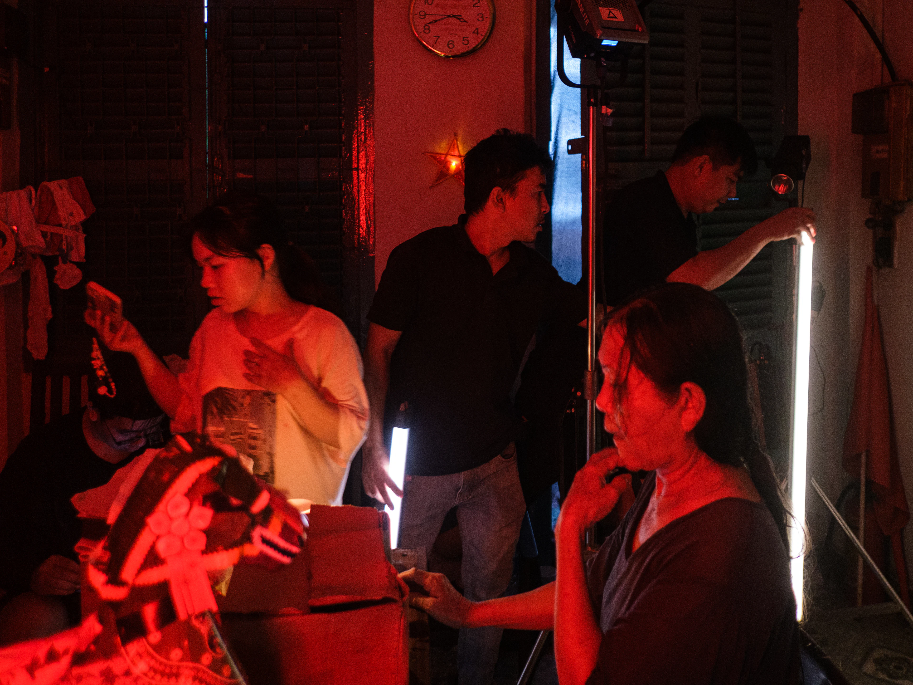 A small crew setting up a shoot in a room lit with red light
