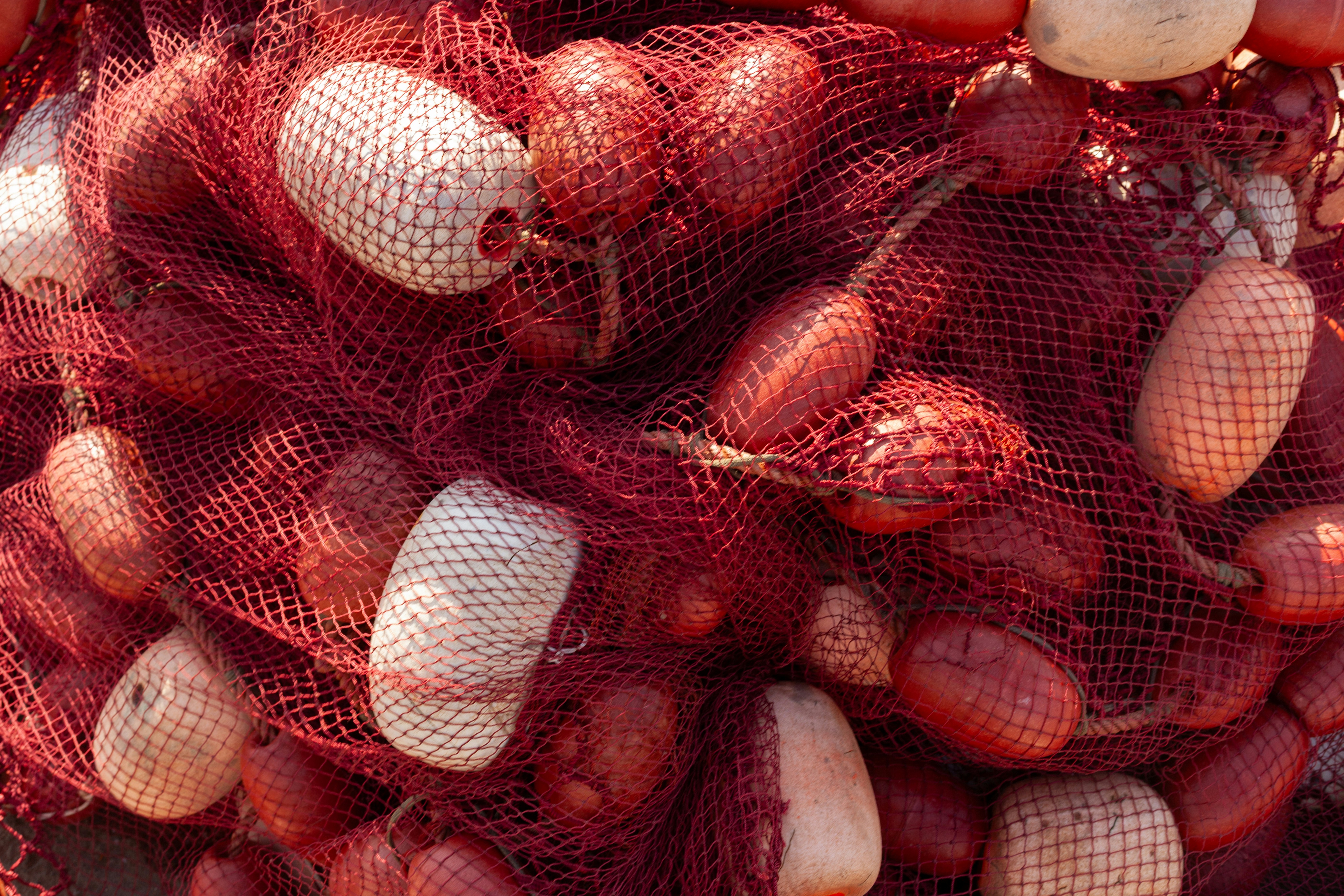 Jaring ikan merah dengan pelampung putih dan merah ditumpuk bersama.