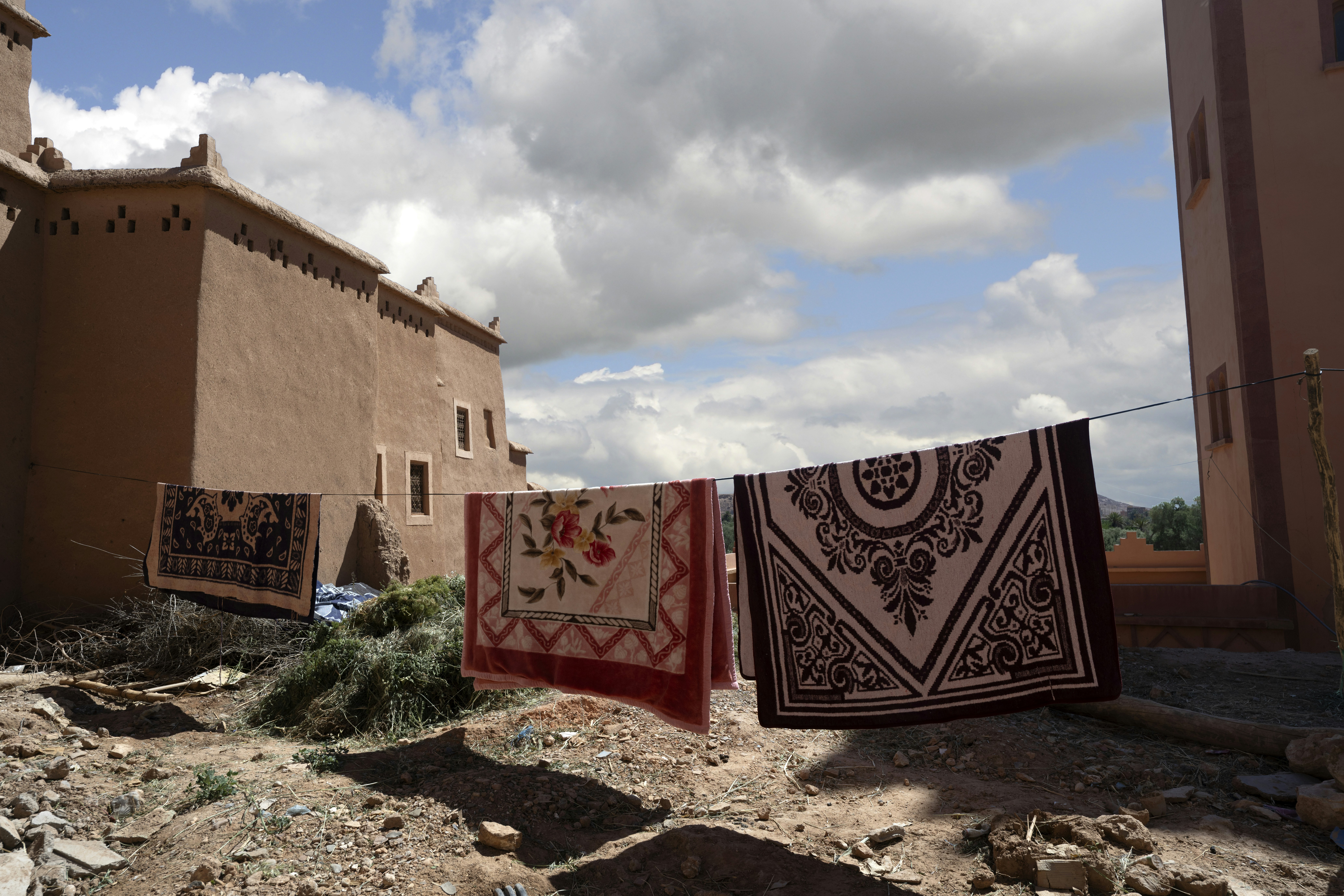 Rugs drying on a clothesline in front of traditional buildings.