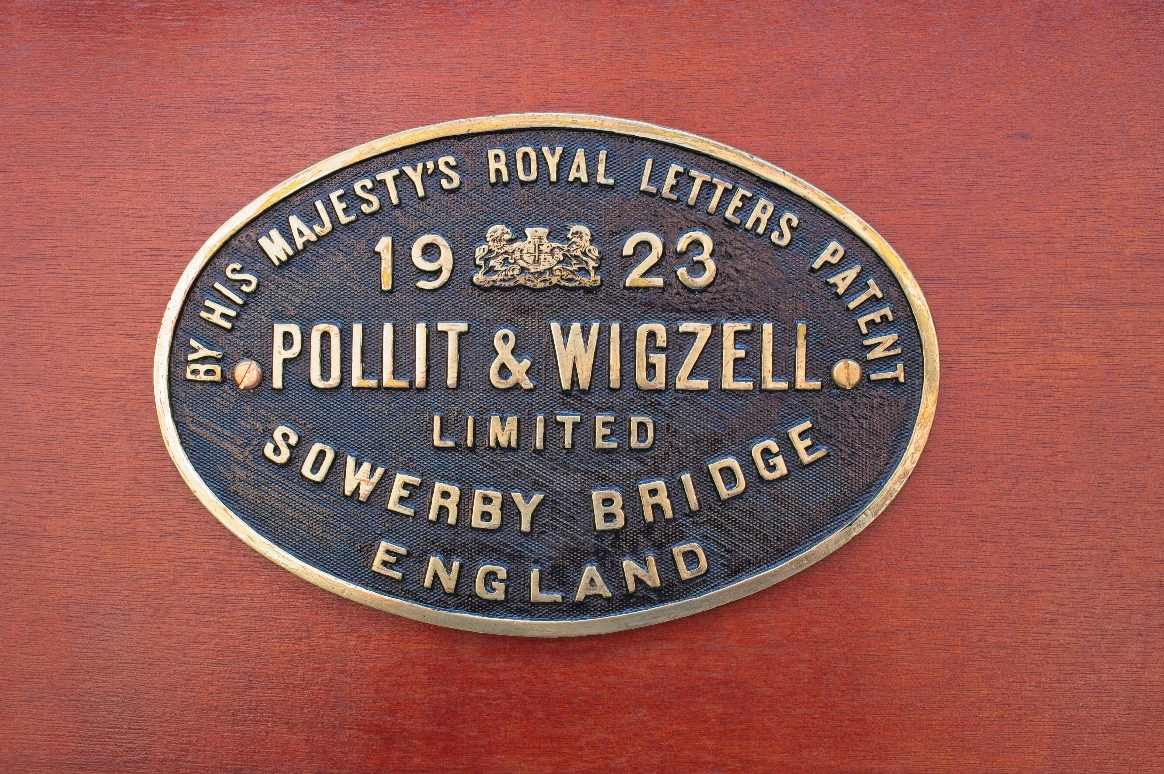 Une plaque ovale en laiton avec le texte « pollit & wigzell 1923 ».