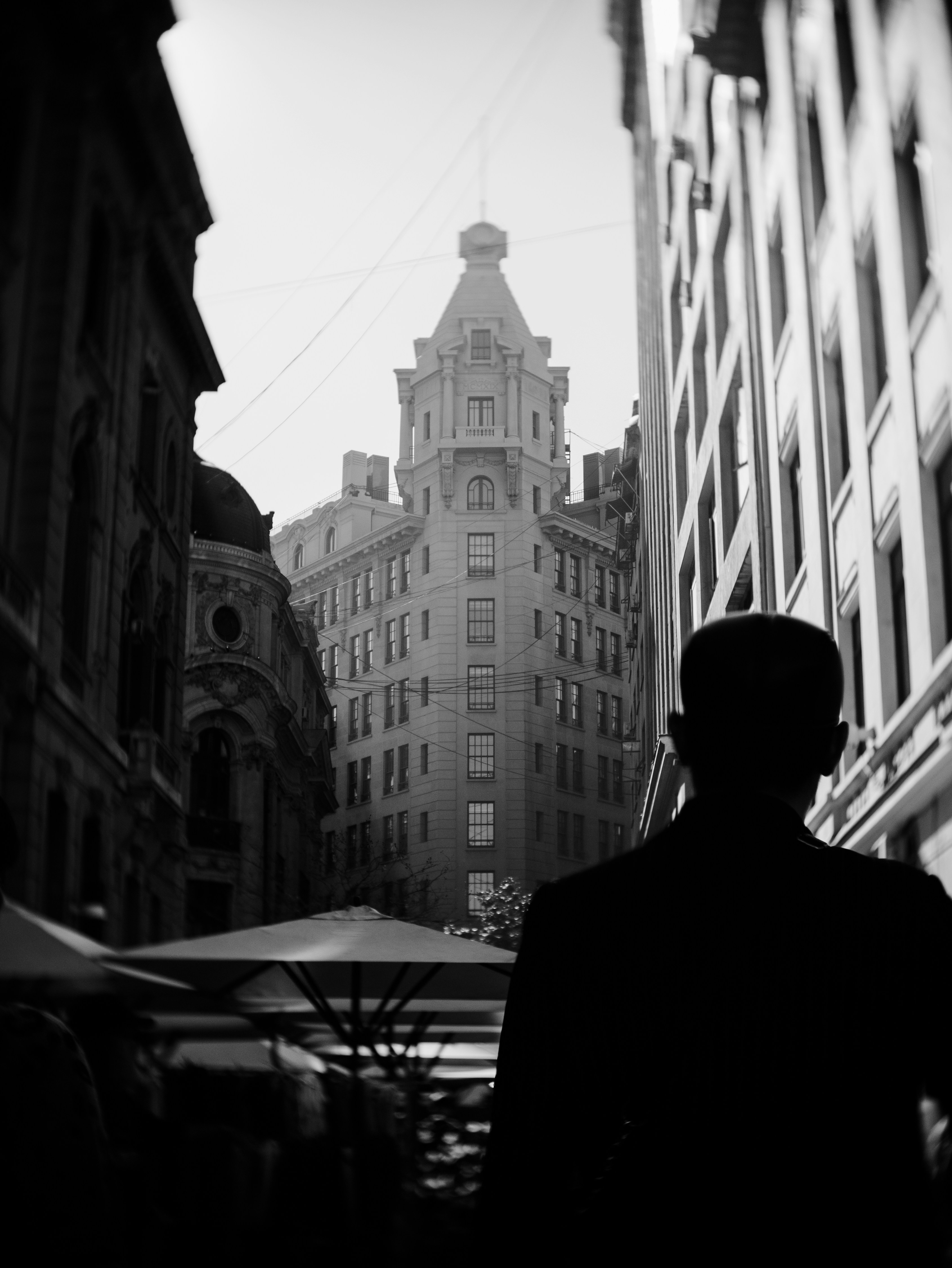 A silhouetted person walks towards a tall, ornate building.
