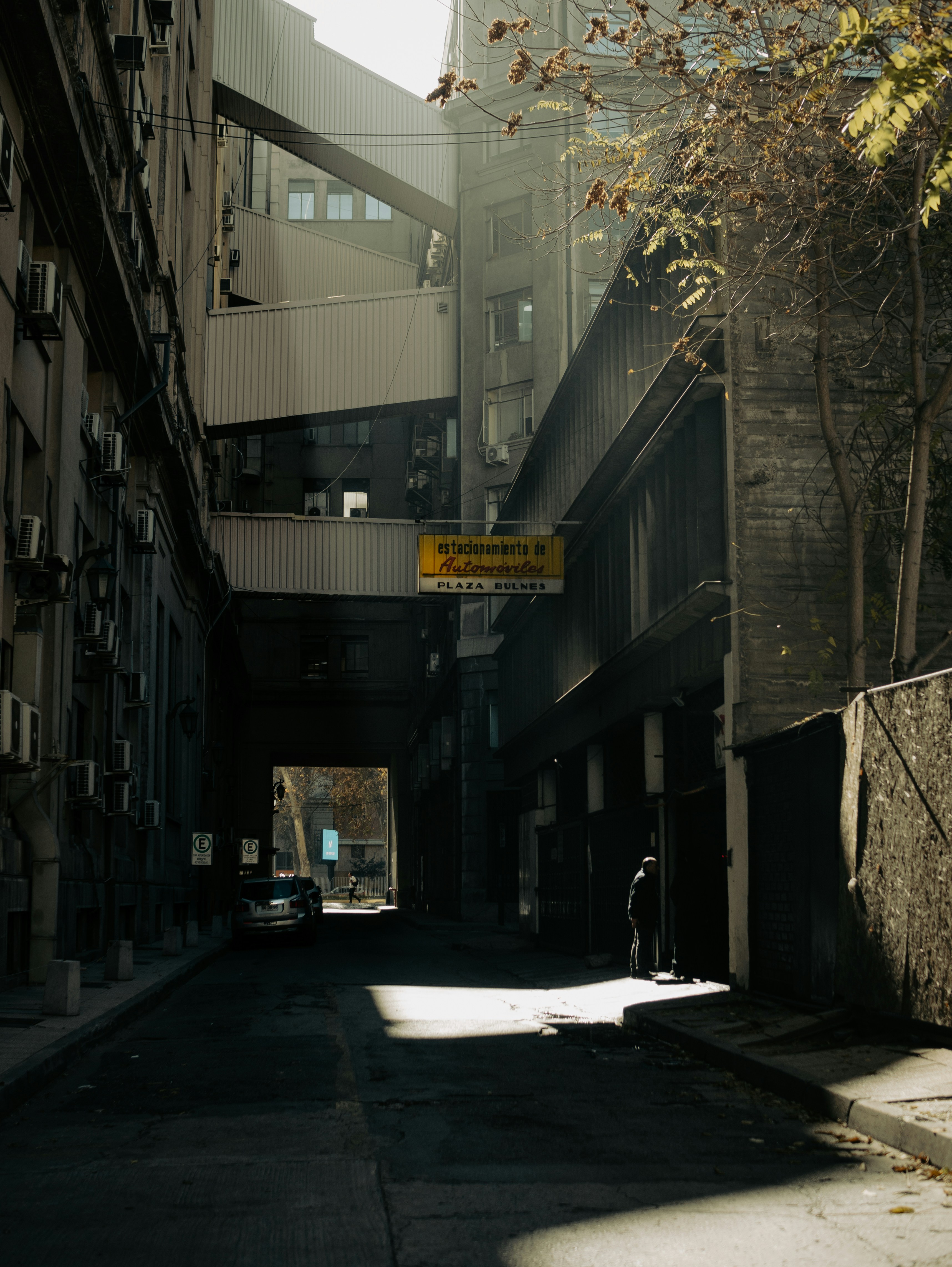 Sunlight illuminates a person in a narrow, shadowed city alley.