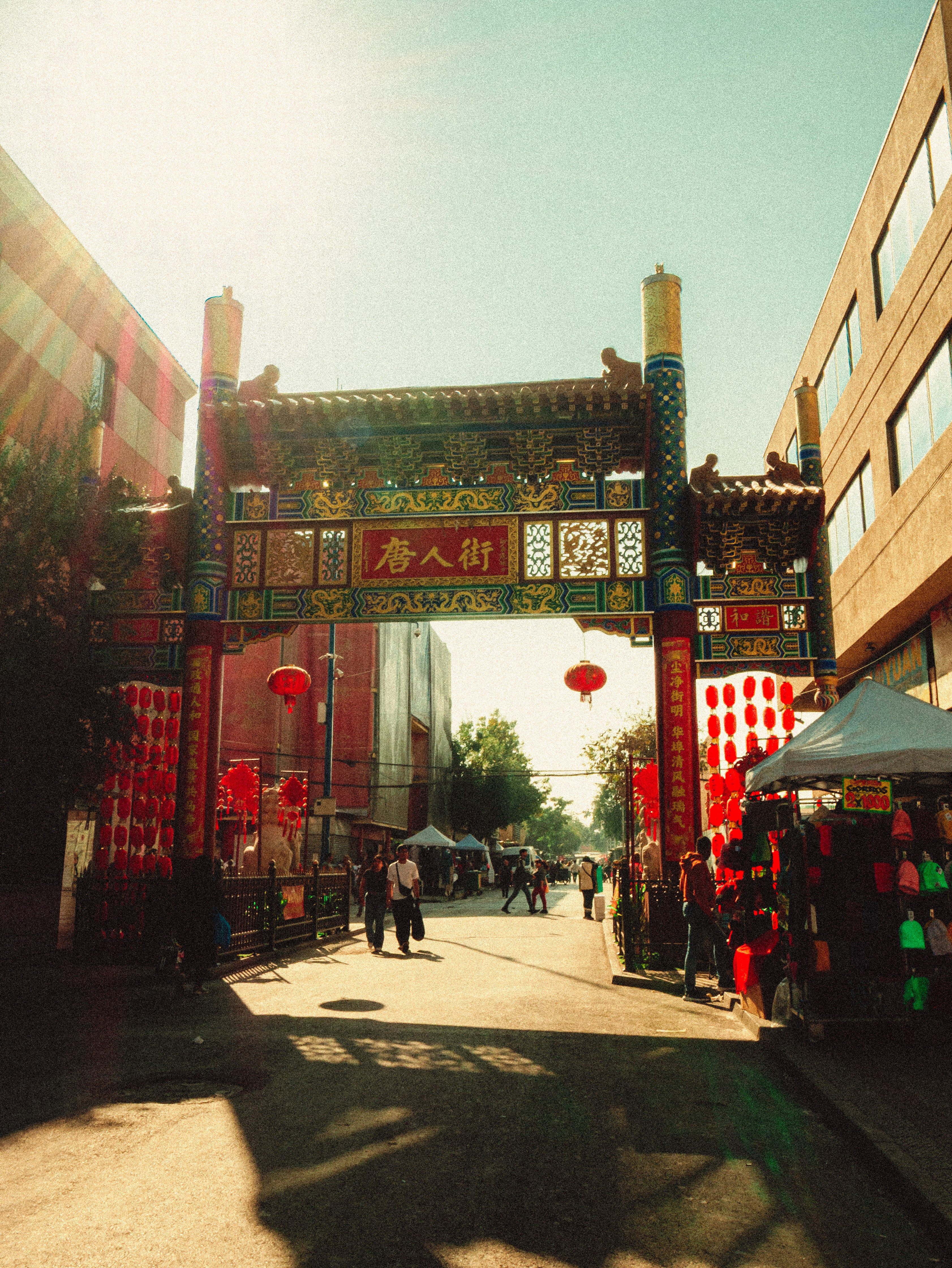 Ornate chinatown gate with red lanterns and market stalls.