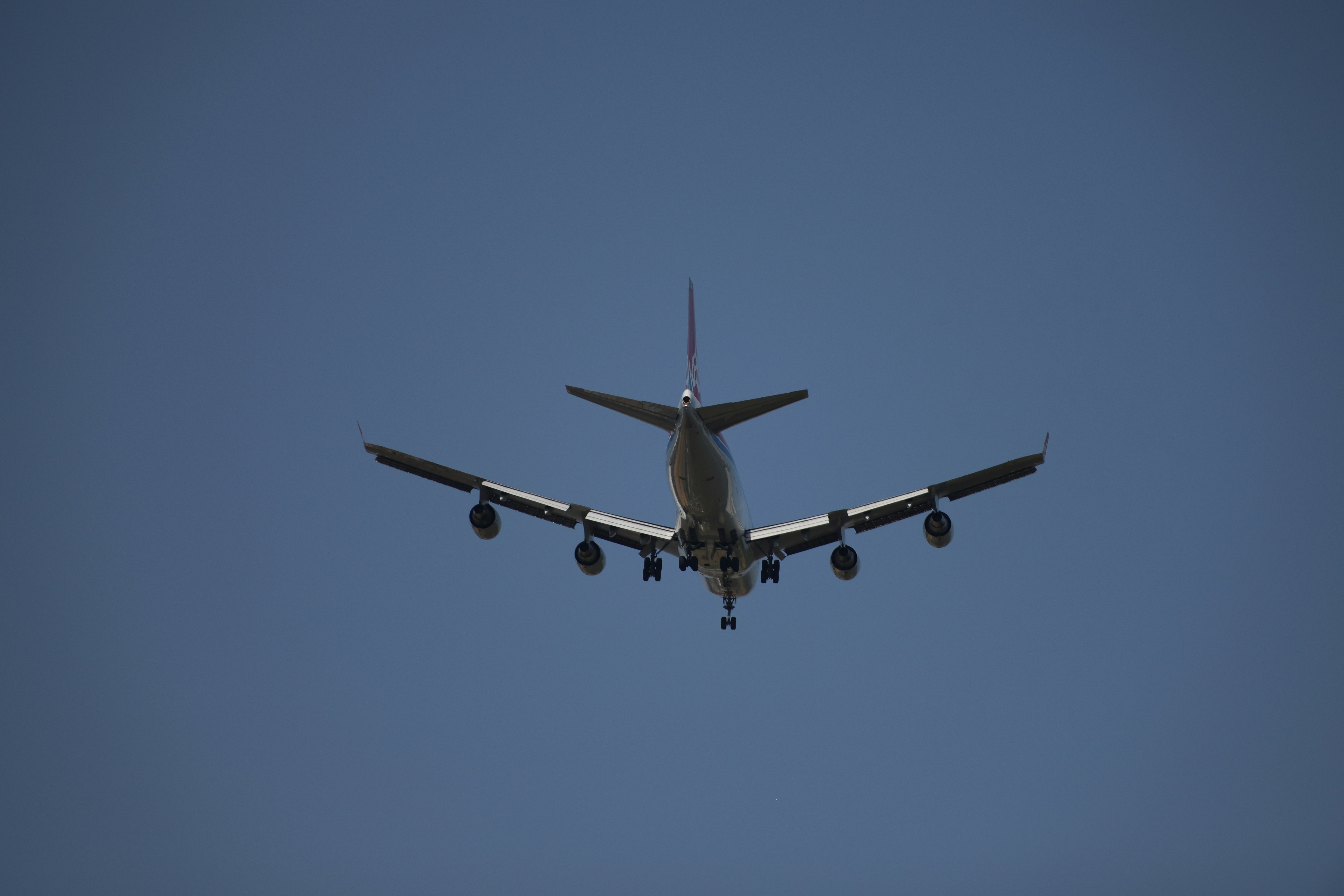 Large airplane flying overhead against a blue sky.