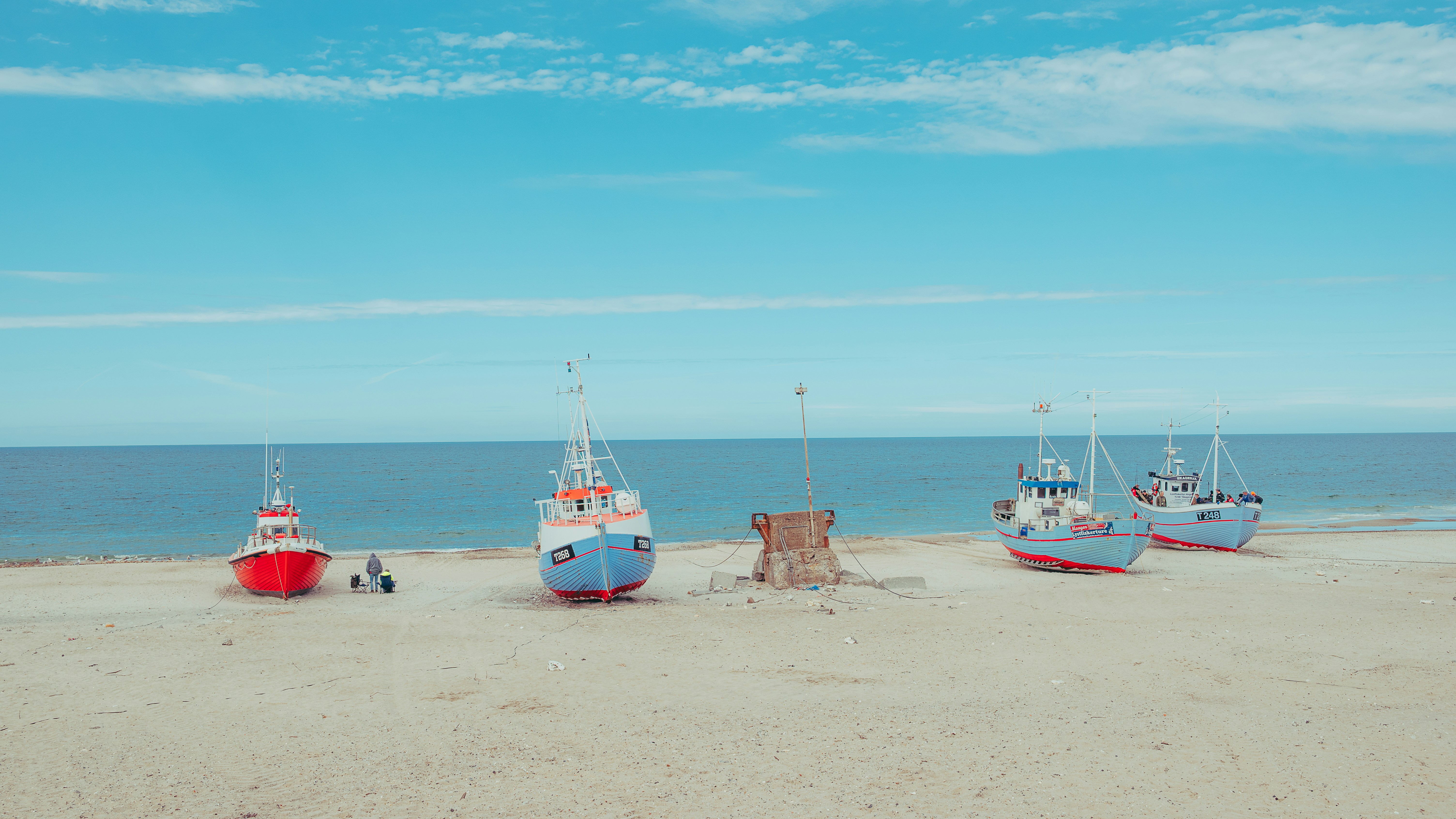 Barcos de pesca en una playa de arena bajo un cielo azul despejado