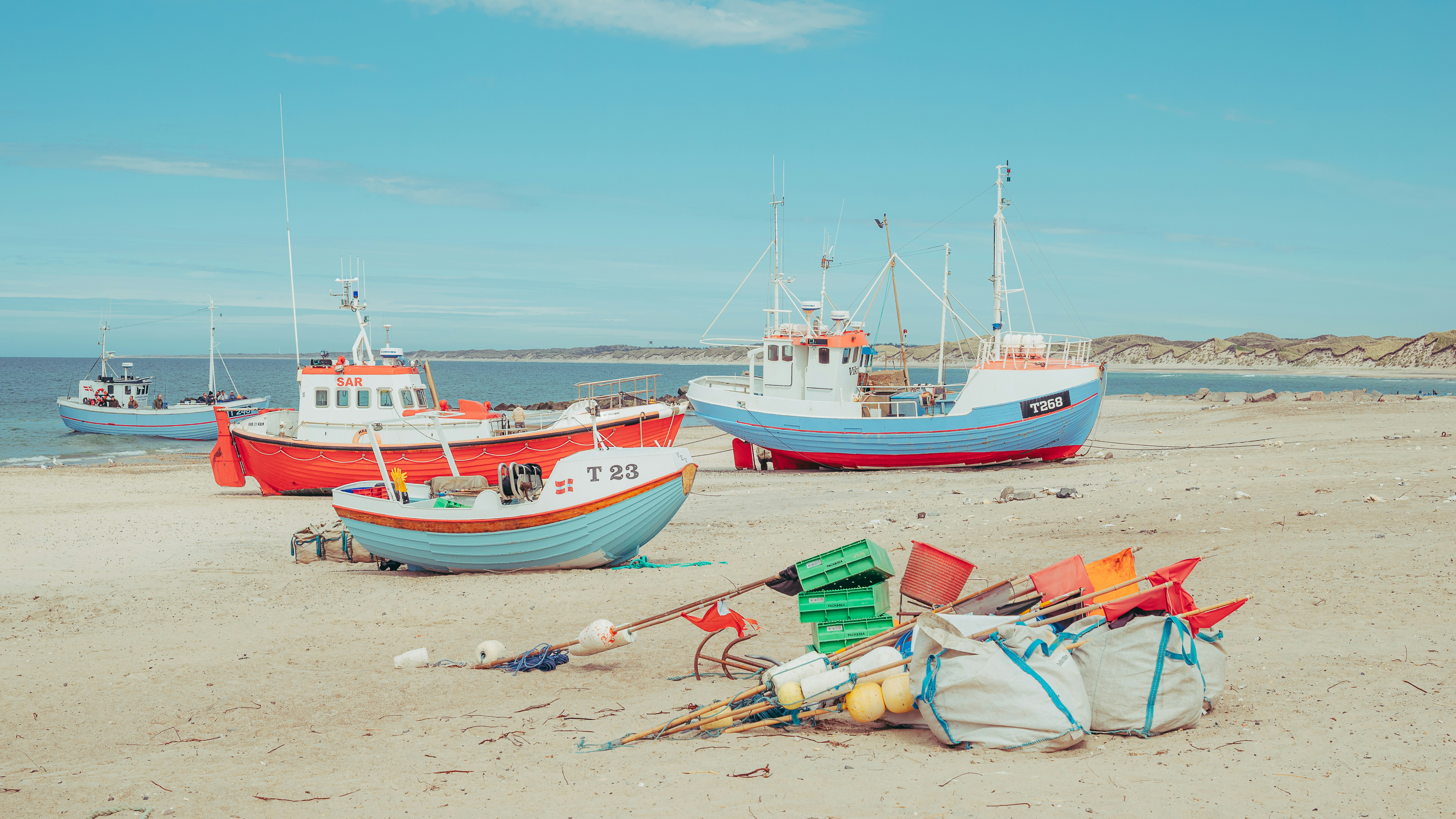 Barcos de pesca coloridos y equipo en una playa de arena