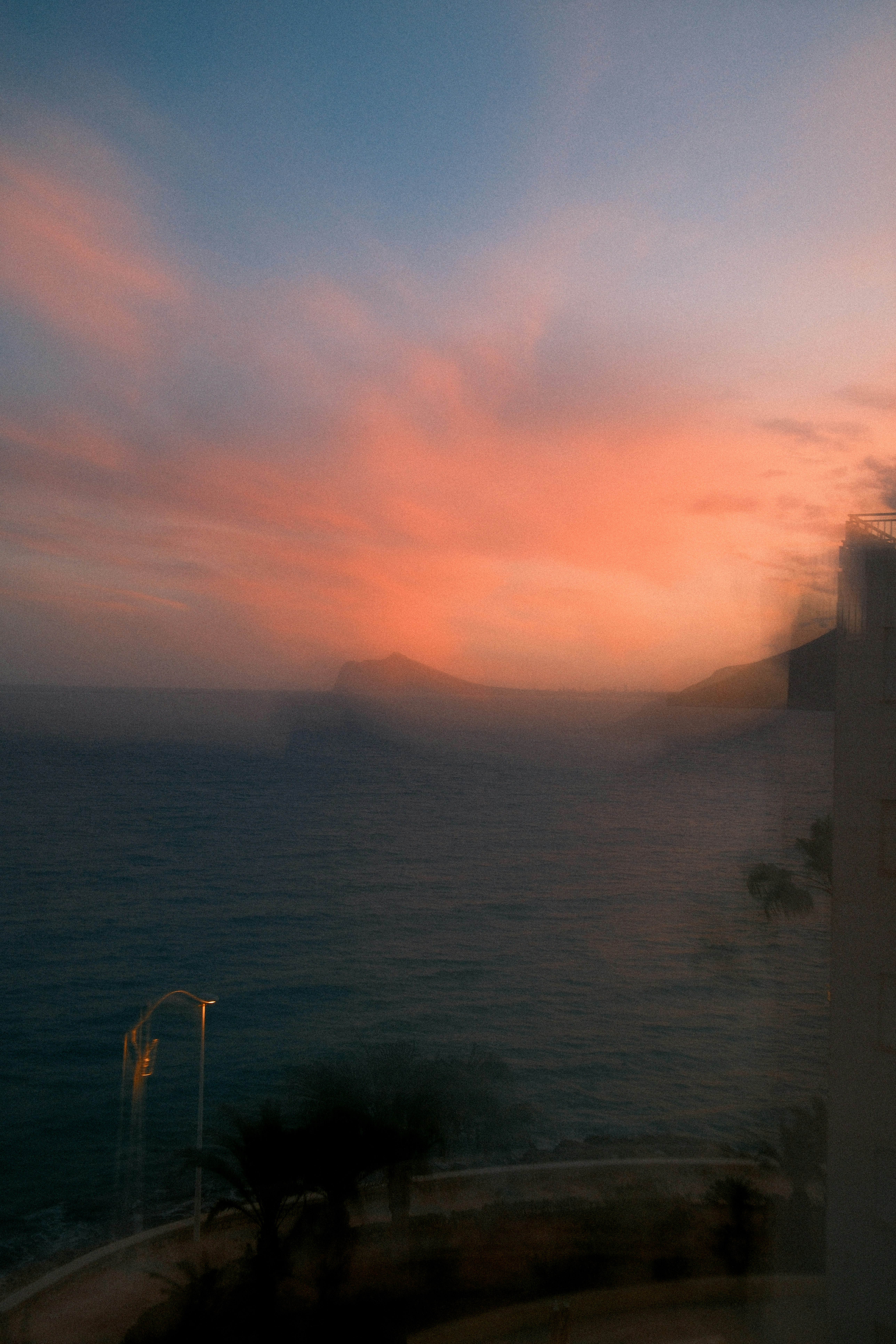 Vibrant sunset over the ocean with distant land.