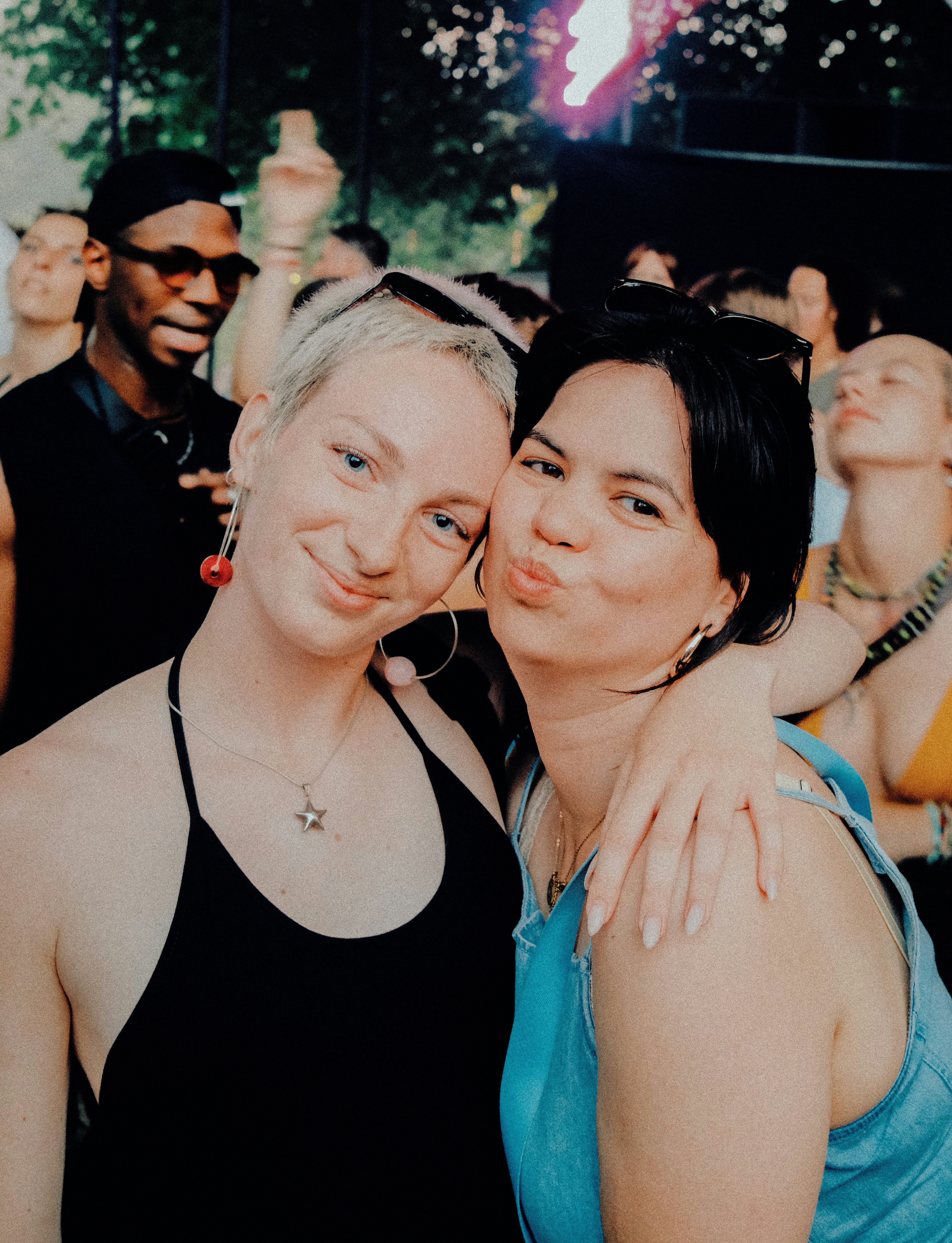 Friends smiling and posing together at an outdoor gathering.