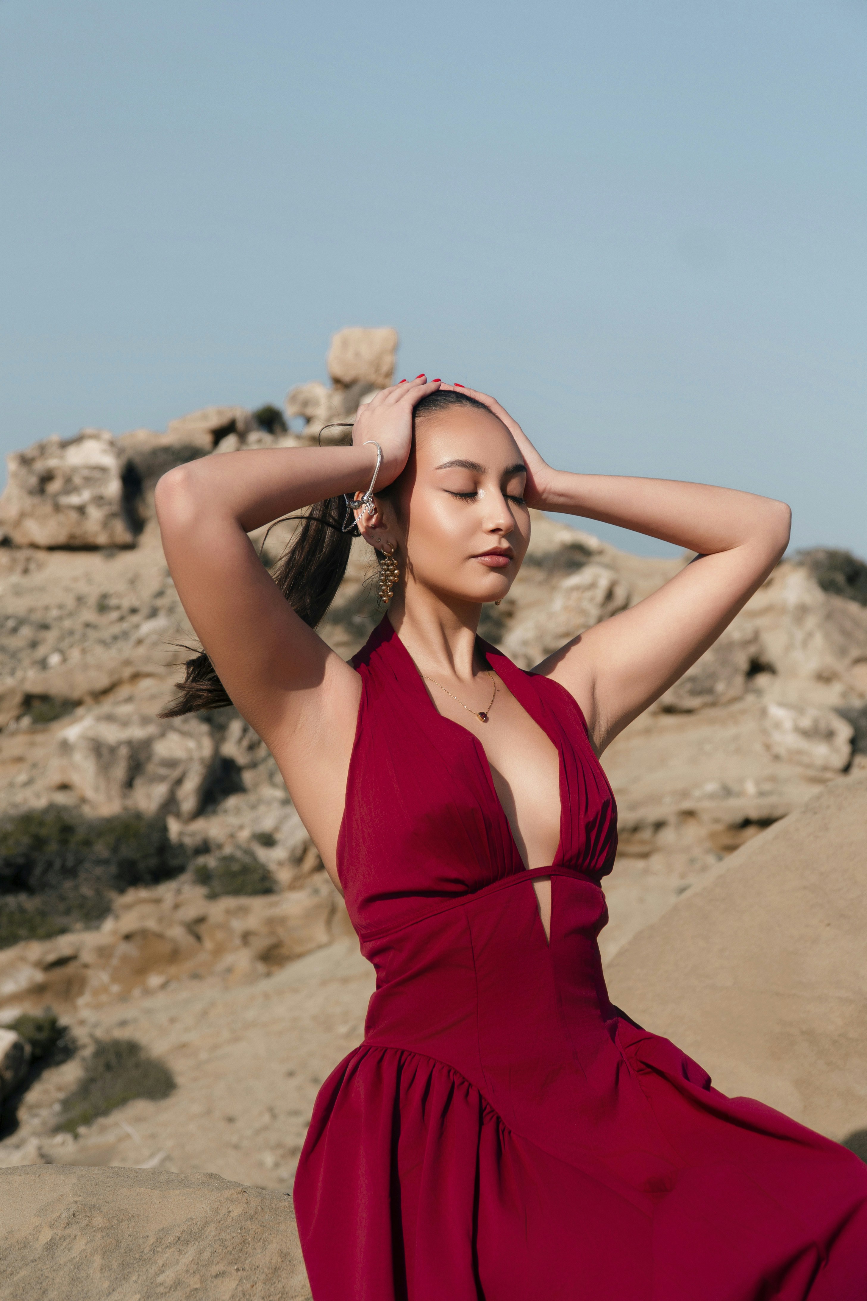 Woman in red dress posing with hands on head